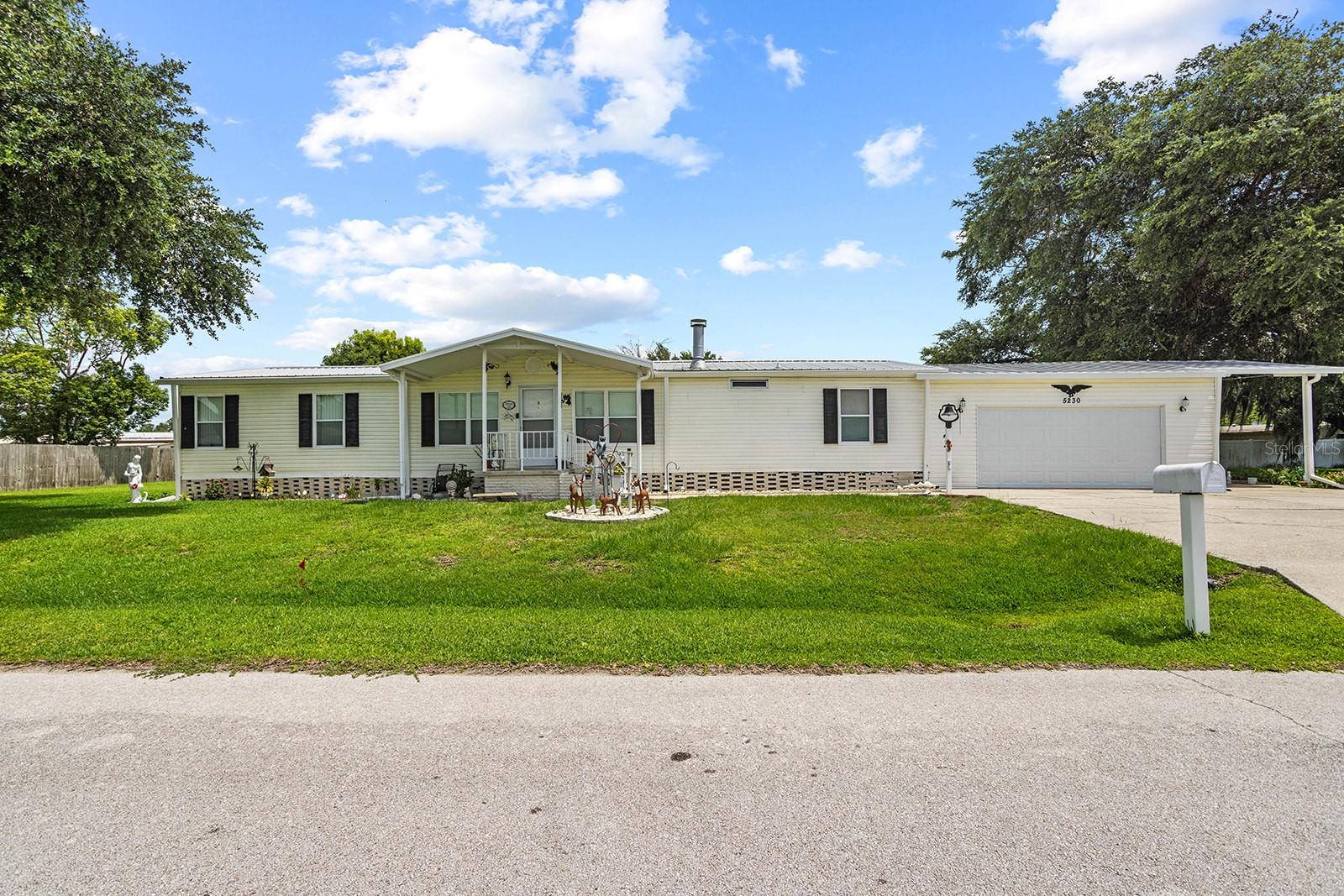 Welcome to 5230 Revelation in Polk City! This spacious 3-bedroom, 2-bath manufactured home offers an open floor plan, generous living spaces, and exceptional parking and storage.
The updated kitchen is the heart of the home and features warm wood cabinetry, granite countertops, stainless-steel appliances, a subway-tile backsplash, recessed and pendant lighting, a center island with seating, and an additional breakfast bar with storage. The kitchen opens to the dining and living areas, creating an inviting space for everyday living and entertaining. The living room is filled with natural light and includes a fireplace with an attractive accent wall and wood mantel.
Luxury vinyl plank flooring extends throughout the home, with carpet in the spacious Florida room. The primary bedroom offers plenty of room and connects to an updated primary bathroom featuring dual sinks, abundant cabinetry, a walk-in shower, and a walk-in closet. Two additional bedrooms provide flexibility for guests, a home office, or hobbies.
Outdoor living is another highlight, with a covered screened porch overlooking the partially fenced backyard. The property also includes a storage shed, mature shade trees, and plenty of usable yard space.
An oversized two-car garage, wide driveway, and covered carport provide excellent parking and storage options, including space for a small RV or boat. With an updated kitchen and primary bathroom, multiple indoor and outdoor living areas, and room for vehicles and recreational toys, this Polk City property offers comfort, flexibility, and so much potential.