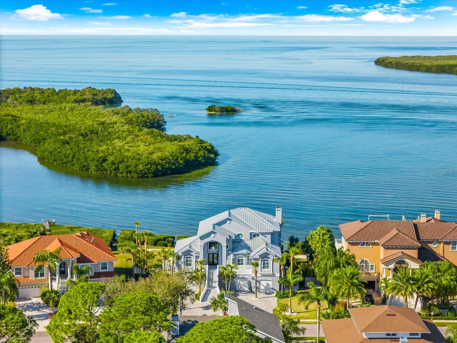 Exceptional Gulf-front estate located within the 24-hour guard-gated waterfront community of Harbour Watch at Pointe Alexis North. Positioned on an oversized 0.55-acre homesite with 134 feet of direct Gulf frontage, this custom-built elevated residence offers panoramic open-water views of the Gulf of America, private dock access, and sweeping sunset vistas from multiple expansive balconies.

Spanning 3,732 square feet of heated living space across three levels, the home is designed for refined coastal living with an elevator, open-concept layout, and high ceilings throughout. The main living level features a spacious kitchen and family room combination with updated quartz countertops, Sub-Zero refrigerator, Wolf gas range, Cove dishwasher, built-in shelving, breakfast bar, and closet pantry. Floor-to-ceiling openings lead to a wide covered Gulf-front lanai, creating seamless indoor-outdoor living. Luxury vinyl flooring and a wood-burning fireplace provide both elegance and durability.

The entire third level is dedicated to the primary suite, offering a private Gulf-front balcony, spa-style bath with hydro-massage tub, dual vanities, and custom California Closets. Three additional guest bedrooms are located on the main living level and include ensuite and Jack-and-Jill bath configurations, ideal for guests or multigenerational living.

Waterfront and exterior features include a private dock with WearDeck decking, ThruFlow decking at the dock end, new pylon wraps, electric and water service, and a 10,000-pound boat lift. The pool area is enhanced by approximately $60,000 in custom stone hardscaping, and pool equipment is elevated on a raised concrete stand for added storm protection. A massive oversized four-car garage measuring approximately 62 by 42 feet offers epoxy flooring, workshop space, and ample storage for boats and recreational vehicles.

Additional highlights include a salt-resistant silver metallic aluminum roof, Generac gas generator, Freedom seven-stage water filtration and salt-free conditioning system, new hot water heater in 2025, hurricane shutters, and negotiable furnishings. Harbour Watch offers a clubhouse, community pool, tennis courts, playground, reclaimed irrigation, and golf-cart friendly streets, all within city limits of Pinellas County. A rare opportunity to own a true Gulf-front estate with direct water access, elevation, and enduring coastal quality.