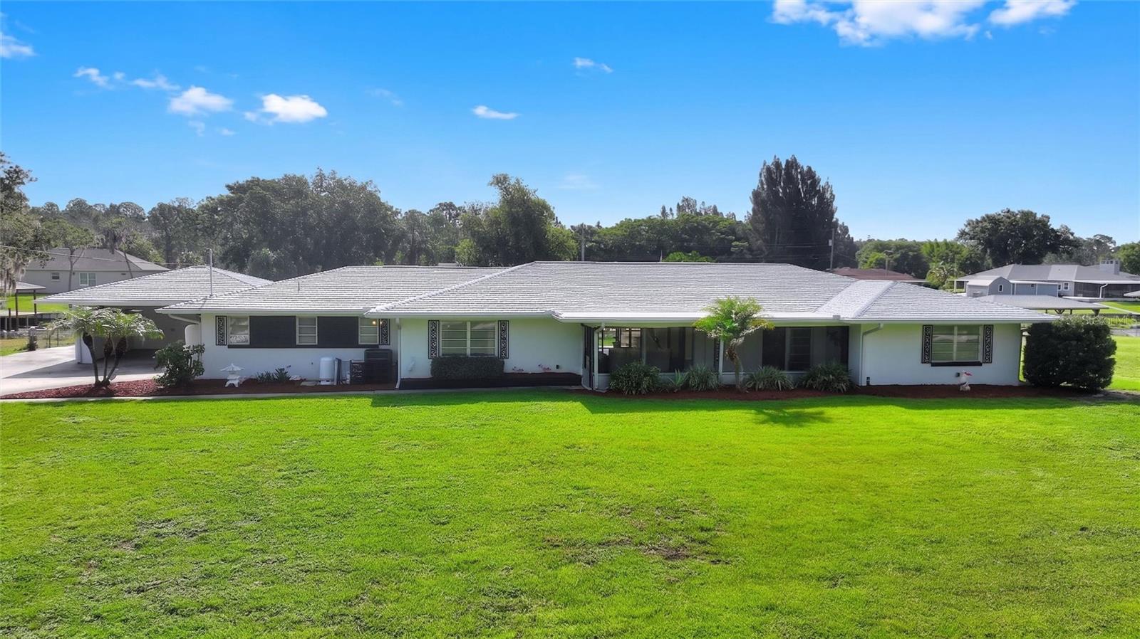 Calling all Mid-Century Modern enthusiasts! This grand lady is waiting just for you! Nestled in the beautiful lake and golf community of Indian Lake Estates, this one-of-a-kind waterfront home offers over 3,000 square feet of living space and more than 3,800 square feet under roof. Featuring timeless architecture, vintage character, terrazzo flooring throughout the formal and informal living areas, and a spacious layout, this home truly lives large!

Your tour begins on the impressive 28' x 5' screened front porch featuring vintage broken mosaic tile flooring. Step inside the welcoming 8' x 11' foyer, where a striking wrought iron room divider showcases the home's authentic Mid-Century Modern design.

To the left are expansive formal living and dining rooms separated by matching wrought iron room dividers. The oversized kitchen offers abundant cabinetry and counter space, two pantry closets, a rolling island, and beautiful views from the kitchen window. To the right is the informal living area featuring a spacious breakfast nook and family room. Sliding glass doors open to the spectacular 34' x 12' sunroom while also connecting to the formal living areas, creating an ideal floor plan for entertaining.

The primary suite features an ensuite bath and walk-in closet. A large guest bedroom and vintage guest bath are also located in this wing. On the opposite side of the kitchen is a second private bedroom suite with its own ensuite bath, exterior entrance, and convenient access to the laundry room, making it perfect for guests or multigenerational living.

The sunroom continues the vintage mosaic tile flooring and features walls of windows overlooking the peaceful canal leading to Lake Walk-in-Water. Outside, the oversized boathouse offers two boat slips, one with a lift, plus a screened sitting area between the slips. Storage is plentiful throughout the home and property.

For added peace of mind, a new roof and new A/C system were installed in 2025.

Indian Lake Estates offers an exceptional Florida lifestyle centered around the 7,528-acre Lake Walk-in-Water, renowned for trophy largemouth bass fishing. Community amenities include a private fishing pier, boat ramp, 18-hole golf course, clubhouse, restaurant, fitness center, library, tennis, pickleball and basketball courts, a lakeside pavilion, and abundant wildlife. Conveniently located near Florida's Turnpike, US Highway 27, I-4, and Highway 60, you're within easy driving distance of Walt Disney World, LEGOLAND Florida Resort, and the beaches of Vero Beach.

If you've been searching for an authentic Mid-Century Modern waterfront home with exceptional space, timeless character, and direct canal access to Lake Walk-in-Water, this remarkable residence is one you won't want to miss!  As an added bonus, this home can come furnished!
