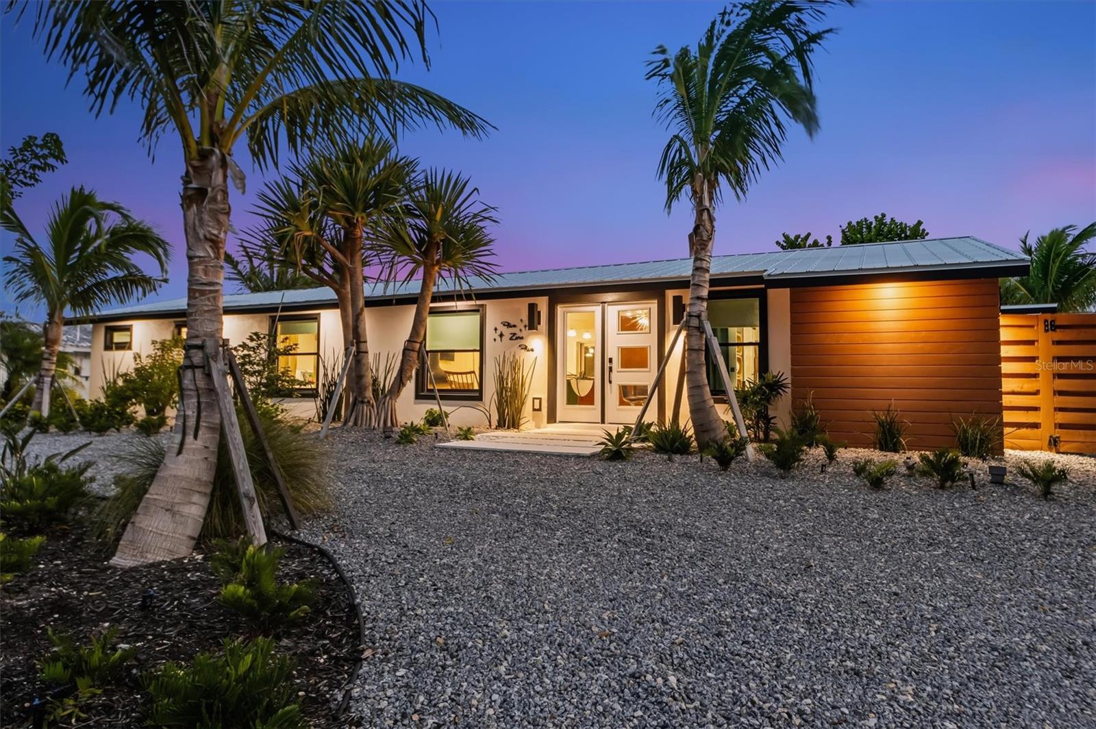 Seller Financing available! Chic Art Deco Canalfront Retreat!  Escape to paradise in this stunning 3 bedroom, 3 bathroom home perfectly blending vibrant Art Deco Palm Springs style with tropical serenity, this residence offers an unforgettable island experience.  Step into a world of bold colors, terrazzo tiles, sleek lines, and retro glamour and a brand new remodel built by Moss.  The open-concept living space flows seamlessly, filled with natural light, vibrant energy, and showcases a floating fireplace designed for both wood or decorative candles, serves as a striking focal point. The gourmet kitchen boasts modern appliances, Eurotech cabinetry, stylish finishes and a pot filler.   Perfect for crafting meals to enjoy by the sparkling, private, heated pool.  The primary bedroom suite is a true sanctuary, featuring a wet bar with a refrigerator, ample storage, and an elegant lighted alabaster countertop. Enjoy the luxury of a walk-in closet and a fabulous en-suite bath with a soaking tub, double vanities, and a large walk-in shower with direct access to the open-air outdoor shower and pool area.   On the opposite side of the home, a spacious second bedroom offers an en-suite bath and sliders leading out to the outdoors. The third bedroom, located just across the hall from a convenient pool bath, includes a washer/dryer and an exterior door, perfect for guests enjoying the pool.  Newly constructed with everything from under-house plumbing to the new electric service, insulation, walls, and floors, this home has been designed for the ultimate comfort and convenience. Outside, enjoy tropical landscaping by Lancaster Design, featuring pavers and turf, along with a sandy area. The brand-new Trex deck, with water and electricity, is perfect for relaxing by the canal, and the 10,000 lb. boat lift provides easy access to the water for boating adventures. This home is being sold turnkey furnished, with a custom golf cart and a 2022 Carolina Skiff included!!  The canalfront location offers direct water access for kayaking, paddleboarding, or simply enjoying the serene views.  Located just minutes from the Gulf beaches, local dining, and vibrant island attractions, this home is a perfect blend of style, comfort, and coastal living!