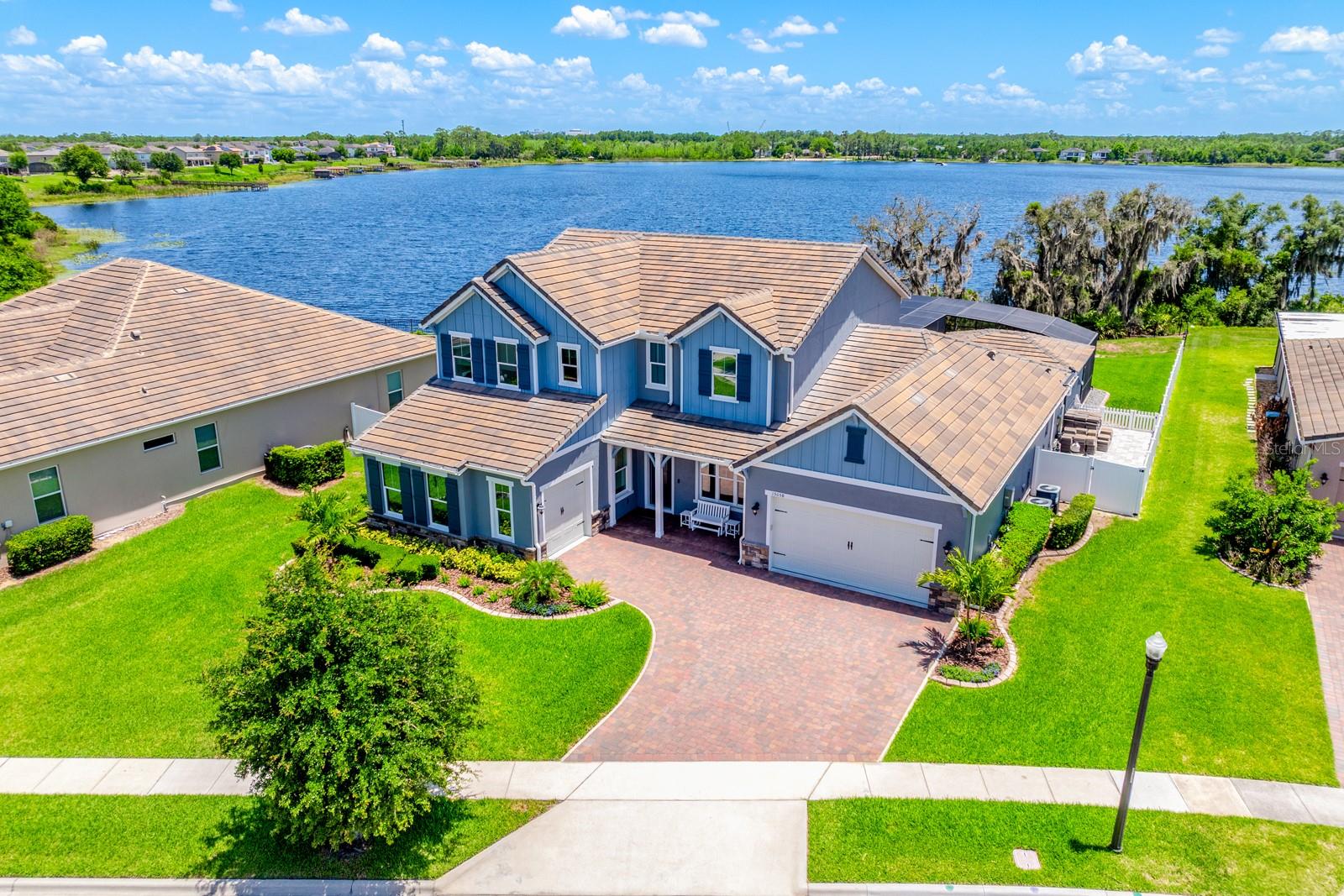 Experience LUXURY ~ WATERFRONT LIVING in this FULLY UPGRADED ~ POOL HOME in the sought-after Highlands at Summerlake Groves community of Horizon West! Built in 2021 and situated on a generous .40 ACRE LOT with a FENCED YARD, this exceptional home delivers breathtaking nightly views of DISNEY FIREWORKS reflecting across the water, creating a spectacular backdrop you can enjoy year-round from the comfort of your own home. Designed with both everyday living and unforgettable entertaining in mind, this home offers an OPEN CONCEPT layout filled with natural light, a dramatic two-story living room with a chic FIREPLACE feature wall, CUSTOM BUILT-INS, and WOOD LOOK TILE flooring throughout the main living areas. The spacious MAIN FLOOR PRIMARY SUITE delivers a private retreat, while a dedicated OFFICE with custom built-in cabinetry and desk space makes working from home effortless. Upstairs, you will find three additional bedrooms and one of the home's most impressive features – a PROFESSIONALLY DESIGNED THEATER ROOM with over $350,000 invested in premium finishes and technology, including a $12,000 projector, professional acoustic treatments, custom wall detailing, and seating for eight. No detail was overlooked when it comes to technology and convenience! Whole-home automation controls music, lighting, outdoor fans, LED lighting, water features, and more with the touch of a button. The WHOLE HOME & POOL SOUND SYSTEM further enhances the experience, while the two-car garage includes its own mini-split A/C system. Additional upgrades include a TILE ROOF, water softener, paver driveway, and separate 1-car and 2-car garages offering ample storage and flexibility. Step outside and discover a backyard designed to rival a private resort. The COVERED LANAI features a fully equipped OUTDOOR KITCHEN complete with a built-in grill, pizza oven, stone flat-top grill, vent hood, and oversized ISLAND for gathering. MOTORIZED SHADES provide privacy and comfort, while the CUSTOM POOL & SPA showcase three WATER FEATURES, dramatic FIRE ELEMENTS, and panoramic LAKE VIEWS. A perimeter mosquito misting system helps maintain a comfortable outdoor environment day and night, allowing you to fully enjoy Florida living year-round. Whether you are boating, skiing, entertaining guests, enjoying a movie night in the theater, or watching Disney fireworks dance across the lake each evening, this home offers a lifestyle few properties can match. Residents of the Highlands at Summerlake Groves also enjoy community amenities and a prime Winter Garden location just minutes from Orange County National Golf Center, the New Independence area, Disney parks, shopping, dining, Downtown Winter Garden, farmers markets, community events, and convenient access to SR 429. Waterfront luxury, state-of-the-art technology, unforgettable outdoor living, and one of the most impressive theater rooms you will find in a private residence – this is the opportunity you have been waiting for. Call today to schedule a private tour!