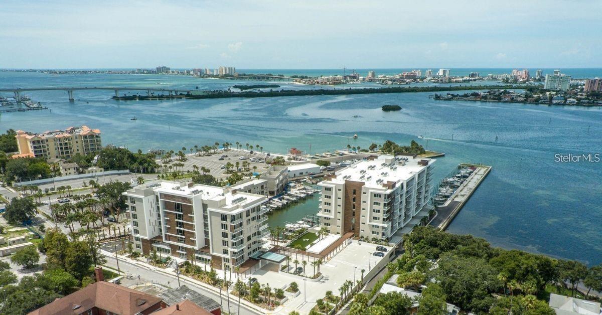 Come experience the pinnacle of luxury living at 920 North Osceola, Unit 801—a rare penthouse in one of Clearwater’s most exclusive waterfront developments. This corner unit dazzles with soaring 12 to 13-foot ceilings, filling the space with natural light and offering sweeping city and water views. The thoughtfully designed 1,800-square-foot floor plan includes two bedrooms, two baths, a den off the kitchen, and a spacious walk-in closet in the primary suite. Modern wood accents, electric shades, and a seamless kitchen-living combo elevate the lifestyle. Two private balconies provide front-row views of both sunrises and sunsets. Nestled directly on the intracoastal, this newer development offers a marina nearby with 69 boat slips and 47 lifts which you can discuss with the marina directly (not connected to this property). Residents indulge in resort-style amenities—a 25-meter lap pool, sauna, steam room, fitness center, putting green, club room with pantry, and 24/7 concierge service. With two garage parking spots (19 and 110), this home is built to the highest modern standards, delivering an unrivaled lifestyle in the heart of Clearwater. Schedule a Showing Today!