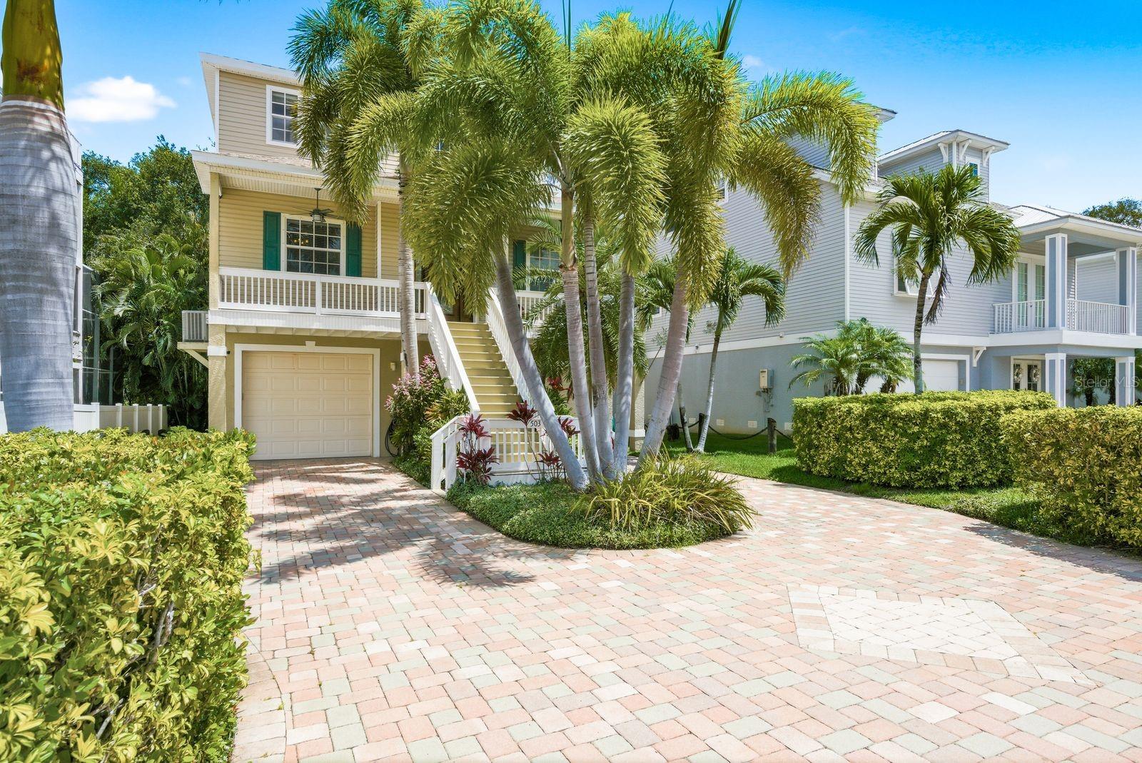 KEY WEST STYLE HOME with COASTAL ELEGANCE - Perfectly elevated and ideally situated just moments from the sparkling waters of the Gulf of Mexico and steps from the iconic Pinellas Trail, this well-built meticulously maintained 3-bedroom 3-bathroom home offers a blend of coastal luxury and active lifestyle living. Step inside to an expansive sun-drenched great room boasting high ceilings that amplify the feeling of spaciousness and a magnificent stacked rock fireplace. The seamless kitchen with breakfast bar, dining and family room combination is perfect for entertaining or cozy nights at home. French doors open onto the private screened porch balcony- your new favorite spot for morning coffee or sunset breezes. Rich engineered hardwood floors and durable tile flow throughout.  The Primary Suite serves as a true sanctuary, featuring a walk-in closet and a spa-like ensuite bath complete with a huge walk-in shower, double-sink vanity and a separate water closet for added privacy. Peace of mind comes from with significant upgrades including; a new ROOF (2024) a professionally updated backyard (2024) and whole house SPRINKLER SYSTEM.  A FOUR- CAR TANDEM GARAGE has plenty of room for vehicles, boat, golf cart, etc.  All this in the heart of Cyrstal Beach close to beaches, restaurants and shopping. This coastal gem is perfect for the Florida lifestyle. Don't miss it!