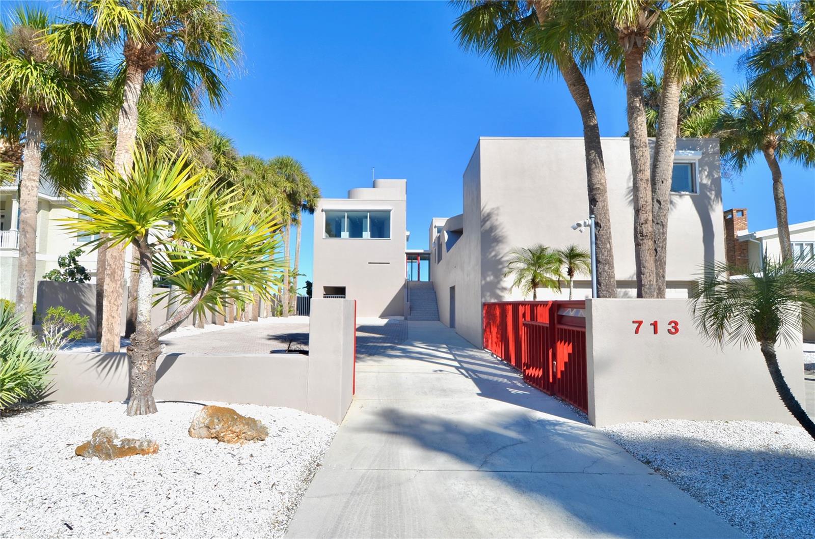 One or more photo(s) has been virtually staged. Bayfront VENICE ISLAND • Designed by architect Carl Abbott • 0.5 mi to Venice Beach • 1.0 mi to Historic Downtown Venice • Roof deck with observation platform.
Set on the bayfront along Roberts Bay, this architecturally significant residence designed by Carl Abbott blends sculptural form with experiential living. Located along El Dorado Drive in Venice, the home spans approximately 4,990 square feet with five bedrooms, 3 full baths, and 3 half baths organized into distinct public and private living zones for both entertaining and retreat. Expansive windows, decks, and open courts frame panoramic water views while maintaining privacy from neighboring properties. The private wing includes a multi-level primary suite featuring a glass floor overlooking the pool and a skylight visible from the ground level, creating a direct visual connection to the sky. Curved interior walls guide movement throughout the home, contrasting with the clean-lined exterior massing. A rooftop observation area offers elevated views of Roberts Bay and the Gulf, the night sky, and beautiful sunrises. Exterior security shutters function as architectural elements while providing heat control and storm protection. Two outdoor environments enhance livability: a west-facing private entrance courtyard and an open bay-side court integrated with the landscape. A deep scuba training pool adds a rare recreational feature, while the attached garage provides secure parking. Conveniently positioned approximately 0.5 miles from Venice Beach and 1.0 mile from Historic Downtown Venice, the property is also close to dining, shopping, cultural venues, parks, golf courses, and the Legacy Trail. This bayfront residence offers architectural distinction, privacy, and proximity to the best of coastal Venice living.