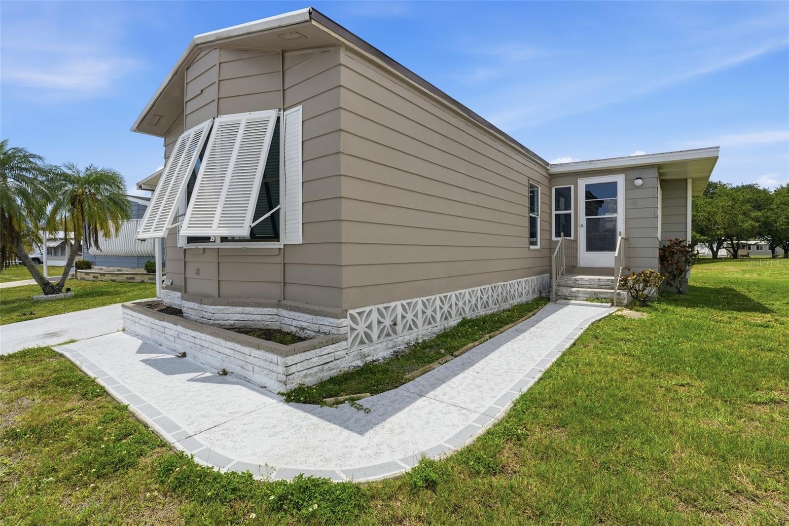 Enjoy affordable Florida living in this well-maintained manufactured home located in the active 55+ community of Holiday Park in North Port. Featuring 2 bedrooms, 2 bathrooms, and an open-concept layout, this home offers comfortable living spaces, abundant natural light, and low-maintenance finishes throughout. With inviting indoor-outdoor spaces and access to a wide variety of community amenities, this property is perfect for enjoying the Southwest Florida lifestyle year-round.

RESIDENCE OVERVIEW:
• 2 Bedrooms | 2 Bathrooms
• Located in the 55+ community of Holiday Park
• Open-concept floor plan
• Luxury vinyl flooring throughout
• Screened patio with attached storage room
• Bright and functional living spaces

INTERIOR FEATURES:
• Open living and dining room layout
• Luxury vinyl flooring throughout the home
• Bright interior with abundant natural light
• Comfortable flow ideal for everyday living and entertaining
• Low-maintenance finishes throughout

CULINARY SPACE:
• Kitchen with all appliances included
• Open connection to living and dining areas
• Ample cabinet and counter space
• Functional layout for everyday convenience

PRIVATE OWNER’S RETREAT:
• Spacious primary bedroom with large windows for plenty of natural lighting
• Built-in closet
• Private en-suite bathroom featuring:
– Single sink vanity
– Walk-in shower

GUEST ACCOMMODATIONS:
• Guest bedroom with built-in closet
• Nearby full guest bathroom for family and visitors

OUTDOOR LIVING:
• Screened patio perfect for relaxing outdoors
• Attached storage room offering additional space for tools, hobbies, or seasonal items
• Ideal setting for enjoying Florida’s year-round sunshine

COMMUNITY HIGHLIGHTS – HOLIDAY PARK:
• Active 55+ gated community
• Resident clubhouse with organized social activities and events
• Two community pools and fitness facilities
• Tennis courts, pickleball, bocce ball, shuffleboard, and billiards
• Library, craft rooms, and recreation spaces
• Beautiful lakes, walking areas, and community green spaces
• Convenient access to shopping, dining, golf courses, medical facilities, and everyday conveniences
• Short drive to Gulf beaches, boating, fishing, and outdoor recreation
• Easy access to US-41 and I-75 for travel throughout Southwest Florida

A wonderful opportunity to enjoy comfortable, low-maintenance living in a vibrant active adult community with excellent amenities and a convenient North Port location.