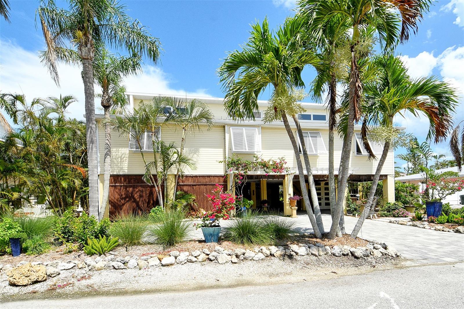 Welcome to Bougain Villa, your Tropical Island Oasis on a deep water canal leading to secluded sandbars, the turquoise waters of the Gulf of Mexico, and several nearby waterfront restaurants.  From the moment you arrive at this magical property, Zen Vibes will calm the mind and put it's whimsical spell on you. Lush plantings, perfectly positioned sitting areas, a private cocktail pool and a custom dock flanked by native mangroves surround this elevated Charmer. Perfectly updated and decorated for maximum pleasure, the vaulted ceilings, clerestory windows providing lots of natural light, and huge back deck enhance the inviting living space and make this home perfect for entertaining indoors & outdoors. Cherry wood cabinetry, a cozy breakfast bar, granite tops, gas range and stainless steel appliances enhance the private kitchen which overlooks the comfortable family room. The primary suite with it's vaulted ceilings and wood floors is totally tucked away, and it's spa-like bathroom with dual sink, separate shower and jetted tub is a perfect retreat highlighted by natural stone and Travertine finishes. The guest bedrooms offer sunrise views, vaulted ceilings and cozy wood flooring and share a Moroccan inspired bathroom. The pecky cypress ceilings, indirect lighting throughout the living space and the colorful interior design and decor are truly special and the enclosed workshop, garage space and gardening sheds below provide additional room for fun. Easy access to miles of Longboat Key's pristine sugar sand beaches where neighbors gather to enjoy spectacular sunsets or just to enjoy a relaxing beach day. The convenience of nearby casual & fine dining, shopping and a short drive to Anna Maria Island's popular night life spots, as well as the Longboat Key Club with resort style amenities, make this the perfect island location for anyone dreaming of living the coveted Florida lifestyle. So come and discover your coastal adventures today on Florida's most prestigious barrier island.