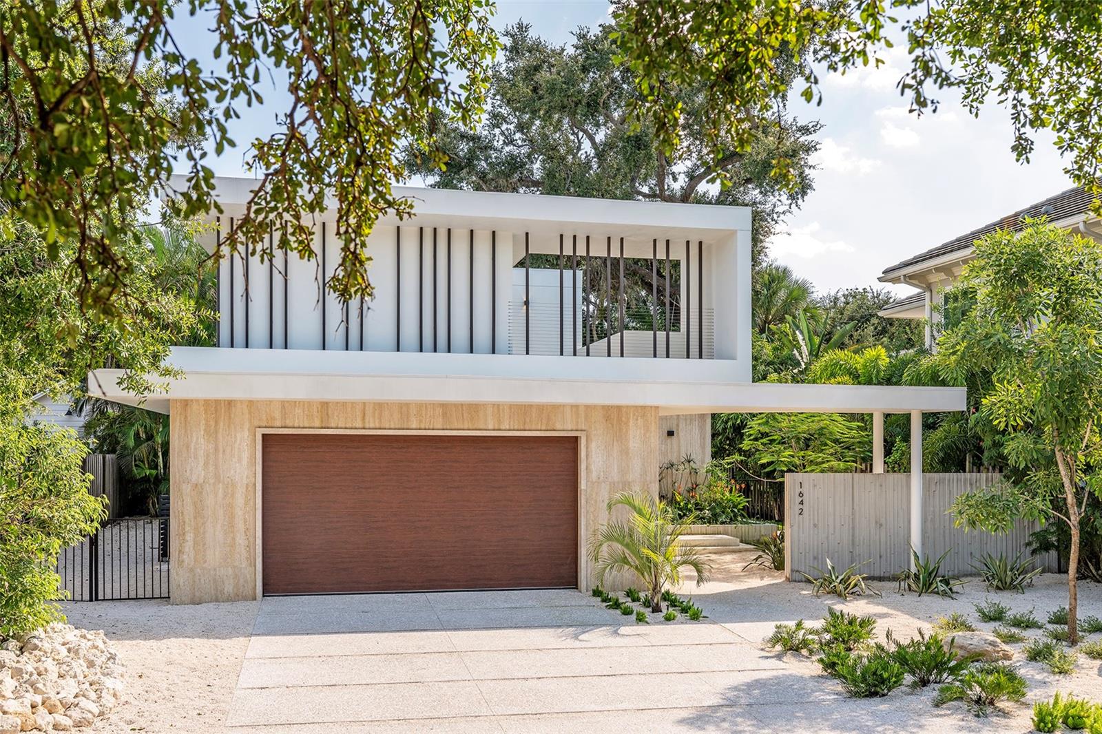 Stunning New Construction by Award-Winning Architect Dan Lear in coveted West of Trail Neighborhood**  This meticulously designed luxury home offers the perfect blend of modern elegance and timeless sophistication. Near Selby Gardens, Morton's Market, and Sarasota Memorial Hospital, this exceptional property provides both convenience and style. Spanning over 3,800sqft of living area, this expansive residence boasts four spacious bedrooms, five full bathrooms, a enormous den with terrace, and a dedicated office space, all thoughtfully crafted for contemporary living. The grand, open-concept great room is the heart of the home, seamlessly floating over the pool area with a stunning large corner pocketing glass door that connects the interior to the beautifully landscaped outdoor oasis. The second floor features three guest suites, each with its own private terrace, offering tropical views and tranquility. The home's striking exterior showcases luxurious vein-cut travertine, creating a refined, sophisticated look. This is an extraordinary opportunity to move right in to a worry free one-of-a-kind masterpiece.