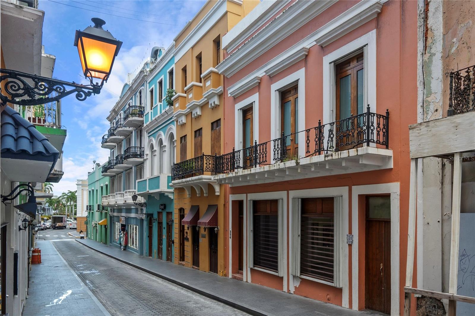 HERITAGE COMMERCIAL PROPERTY ON FORTALEZA STREET.   
Just steps from Plaza Colón, at the gateway to Old San Juan, this heritage commercial property embodies the city’s historic pulse and cultural vitality.  Positioned on the Eastern end of the iconic Fortaleza Street, one of the city’s most bustling thoroughfares, this historic mixed-use building is surrounded by eateries, boutiques and specialty shops, with the city’s main parking garages less than a block away.  This stretch of Fortaleza runs adjacent to Plaza Colón, which remains one of San Juan’s most emblematic squares.  Historic landmarks like Teatro Tapia and the Antiguo Casino Español form the plaza’s perimeter, while a marble statue of Christopher Columbus rises at its center.  This storied setting situates the property within the cultural and civic heart of the old city, where heritage and daily life converge.  

Floor-to-ceiling glass windows decorate the building’s façade and reveal over 3,000 square feet of open-plan space.  Currently curated as an art gallery, the first level of the building features soaring beamed ceilings, modern lighting, and central air conditioning. Sweeping arches lead to a dramatic interior patio and a central atrium that extends vertically through the height of the building.  Enclosed in glass, this imposing architectural feature bathes every floor with natural light, while shielding the interiors from direct exposure to the elements. The main stairwell runs parallel to the central atrium, while a secondary stairwell provides direct access to the second and third levels from the street.  

A contemporary office space awaits on the second level with five main offices and a generous reception area, as well as a spacious executive suite that doubles as a conference room and opens to an enchanting balcony with views of Fortaleza Street.  The third level, which has been brought to shell condition, is a blank canvas awaiting transformation into a private residence, creative studio or additional commercial space.  Natural light pours in from the central atrium, while a generous terrace provides additional outdoor space. Above it all, a sweeping rooftop crowns the property, offering privileged city views and the opportunity to develop additional space for entertaining guests or hosting private events.  

Offering a rare combination of historic character and functional design, this building stands out as one of Old San Juan’s most versatile mixed-use properties and provides a singular opportunity for investors, entrepreneurs, and visionaries, to steward one of Fortaleza’s defining addresses into its next era.
