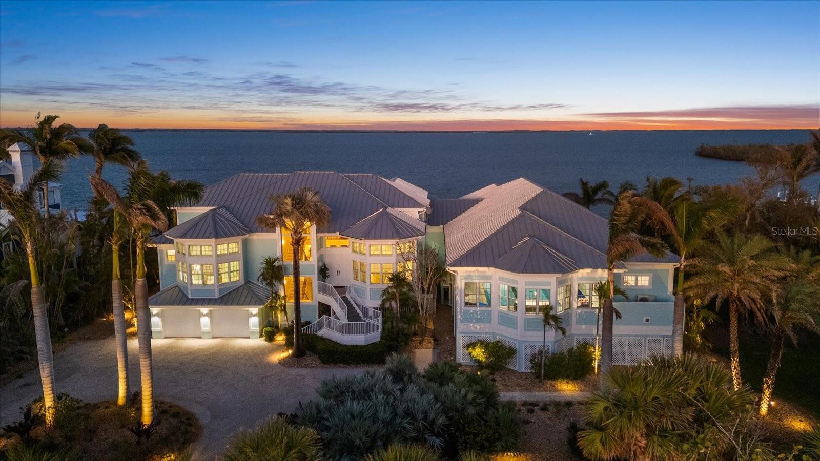 2 DEEP-WATER DOCKS AND A COVERED 7,000 LB LIFT. 5 BEDROOMS AND 5.5 BATHROOMS. MYRTHA POOL. INDOOR GUN RANGE. NO FIXED BRIDGES TO GULF WATERS. ROOF 2017. Welcome to a true Sportsman’s Paradise at 14 Grouper Hole Drive on Gasparilla Island in Boca Grande, Florida. This exceptional waterfront estate offers an unparalleled lifestyle, where breathtaking views of the Gasparilla Sound greet you the moment you step through the grand double doors. Designed for both adventure and relaxation, this residence seamlessly blends refined elegance with world-class amenities. The main living area is on the second floor, accessible by a three-stop elevator. A bright foyer leads into the expansive living room, which is open to the third floor, creating an impressive sense of space with soaring ceilings. The dining area flows effortlessly into the kitchen, where a beautiful bay window breakfast nook offers the perfect setting to enjoy morning coffee with stunning water views. The kitchen features a WOLF gas stove, a Sub-Zero paneled refrigerator, a spacious pantry, and a breakfast bar. French doors from the living room open onto a large screened deck—ideal for entertaining or unwinding as boats pass by. The second floor hosts three guest bedrooms, each with nearly floor-to-ceiling windows and en-suite bathrooms. A half bath and a well-appointed laundry room are also on this level. A striking catwalk on the third floor, adorned with a sculptural iron railing, overlooks the living space below while offering sweeping views of the Sound. The luxurious primary suite is a serene retreat, with private access to an open-air deck to enjoy the waterfront breeze. The en-suite bath features dual vanities, a walk-in shower, and a separate soaking tub. A generous walk-in closet with custom shelving provides ample storage. An additional sitting area with a bay window offers yet another breathtaking vantage point. A well-appointed fifth bedroom, also with mesmerizing water views and an en-suite bath, is located opposite the primary suite. The estate’s crown jewel is the extraordinary sports pavilion, seamlessly connected to the main home. Designed for ultimate recreation, it features an indoor/outdoor sitting and dining area with a retractable mosquito screen and fire pit. Inside, a stylish living space and fully equipped kitchen boast Viking appliances, Kendall Cambria Quartz countertops, a built-in bar refrigerator, and an ice machine. At its heart is the Myrtha Ozone Pool—one of Florida’s most advanced residential pools. Competition-length, with stainless steel bolted technology for durability, it features a European lighting system, the only one of its kind in North America. Exceptionally pure, the water is free of chlorine and salt, making it pristine enough to drink. The pool is both heated and cooled for year-round enjoyment, with a standalone hot tub nearby. Remote controlled hurricane shutters add to piece of mind.  The sports pavilion also includes a private, air-conditioned Pilates studio and areas for ping pong and pool. For shooting enthusiasts, the state-of-the-art gun range features two dedicated lanes—one for archery and one for firearms. Equipped with a high-tech camera system for precision accuracy, a retractable target retrievals, advanced bullet entrapment, and sound suppression, this range ensures top tier performance.
