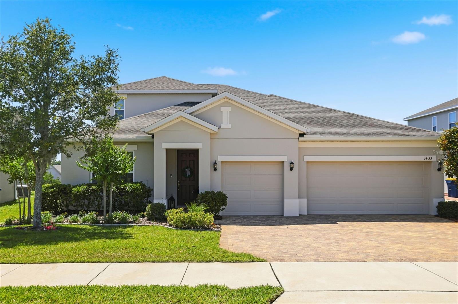 Welcome to 1433 Shira Rd, a stunning two-story residence in the sought-after Ardmore Reserve community of Minneola, nestled in the rolling hills of Lake County with panoramic views of the natural hillside that serve as your private backdrop. From the moment you arrive, the curb appeal is undeniable: a two-tone architectural stucco elevation, paver driveway, and manicured landscaping freshened in 2026 create a polished first impression. Step through the front door into a grand foyer, where large-format tile flows through every main living area for stylish, low-maintenance, and allergen-free living. The open-concept floor plan connects a formal living space or flex room, chandelier-lit dining room, and a spacious family room that opens through floor-to-ceiling sliding glass doors to the covered, screened lanai. At the center of the home is a chef-worthy kitchen featuring rich 42-inch espresso cabinetry with crown molding, white quartz countertops, a mosaic tile backsplash, a gas range, and stainless steel appliances throughout. The oversized island with pendant lighting anchors the space, with open sightlines to the family room. The primary suite is located downstairs and a genuine retreat with tall ceilings, a large picture window, ample closet space, and a spa-inspired ensuite bath. Featuring dual vanities with white quartz tops, a tiled walk-in shower with frameless glass enclosure, plus a decorative accent strip and chrome fixtures, this bath is both functional and modern, designed to accommodate a variety of households. Secondary bedrooms are generously sized and share well-appointed bathrooms with matching cabinetry and dual sinks. A full dedicated laundry room with washer and dryer included rounds out the lower level. Upstairs you'll find a generously sized 5th bedroom with ensuite full-bath that's perfect as a guest retreat or private room for multi-generational households. The covered, screened lanai is the perfect place to watch a Florida sunset, BBQ with friends, or sip a cup of morning coffee. The backyard backs to sprawling hillside with open and unobstructed views, offering a level of privacy that is increasingly rare. The major systems are essentially new: a newer Square D electrical panel, PVC plumbing, and a gas water heater all in great condition. Washer, dryer, refrigerator, all ceiling fans, chandeliers, window treatments, and framed bath mirrors all convey, making this home better than new with tens of thousands of upgrades and furnishings that builders increasingly leave out. Ardmore Reserve offers a resort-style pool, splash pad, cabana, and playground with no CDD and a low quarterly HOA. Five minutes to the Florida Turnpike, minutes to AdventHealth Minneola, and zoned for Grassy Lake Elementary, East Ridge Middle, and Lake Minneola High School. Schedule your showing today.