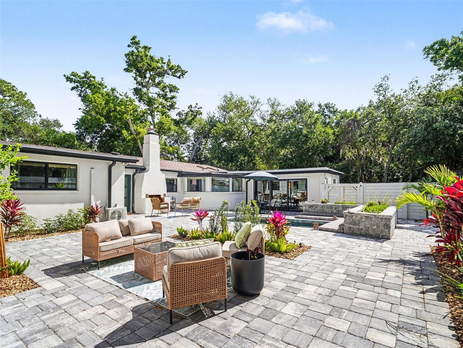 Step into a home that redefines privacy, design, and sophistication.  Priced at $865,000, this fully renovated 3-bedroom, 3-bathroom residence with a dedicated office and pool offers a rare courtyard-style layout where indoor and outdoor living seamlessly intertwine.  Enter through a private gated front courtyard, and you’re immediately welcomed by a heated pool, custom pavers, and a striking outdoor wood-burning fireplace.  Cement planters with cushioned seating surround the pool, creating a relaxed resort-style setting, while a lemon tree and foliage add a natural, tranquil touch to the courtyard oasis.  This is an intimate, resort-style setting designed for both private entertaining and everyday living.  The oversized screened lanai extends your living space even further, creating multiple areas to relax and unwind in complete privacy.
Inside, modern upgrades marry timeless design across a beautifully connected living and kitchen layout.  The living room is anchored by a sleek electric fireplace and a mounted picture frame TV against a green tile backsplash, creating a refined focal point that feels both comfortable and elegant.  The kitchen is equally impressive, featuring quartzite countertops, floor-to-ceiling custom cabinetry, custom dishwasher drawers, and a pot filler above the gas stove.  Seamlessly integrated appliances, including a refrigerator concealed within matching cabinetry, enhance the clean, elevated aesthetic.  A hidden “secret” door within the kitchen leads to a spacious laundry room and full bath, adding practicality while introducing a subtle element of surprise. 
The private office is another standout feature, finished with marble flooring and framed by large windows overlooking the courtyard and pool.  Abundant natural light and serene views create an inspiring workspace, while French doors provide privacy when needed.
New engineered wood flooring flows throughout the home, complemented by updated lighting and new hurricane impact windows and doors for peace of mind.
This home offers the rare advantage of two primary suites, each refined in every detail. The main suite is a true retreat, featuring a private dry bar with a mini fridge, a fully customized 7x17 walk-in closet, and a spa-inspired bath with a soaking tub, expansive walk-in shower, heated towel rack, smart toilet, and designer finishes in warm, sophisticated tones.  The second suite provides its own spacious bath and beautifully finished walk-in shower, ideal for guests or multigenerational living.  The third bedroom has beautiful views of the pool through the sliding glass doors.
Additional upgrades include a whole-home water filtration system, split A/C units for enhanced cooling, an attic fan, and new fencing surrounding the courtyard.  Parking is abundant with a circular driveway and additional space alongside the fence, comfortably accommodating five or more vehicles.  A separate outdoor shed provides convenient storage for lawn and pool equipment.  Located in a quiet neighborhood just a few streets from the water, this home is a rare find in today’s market, where every detail has been carefully curated for luxury, comfort, and style. Furnishing negotiable!