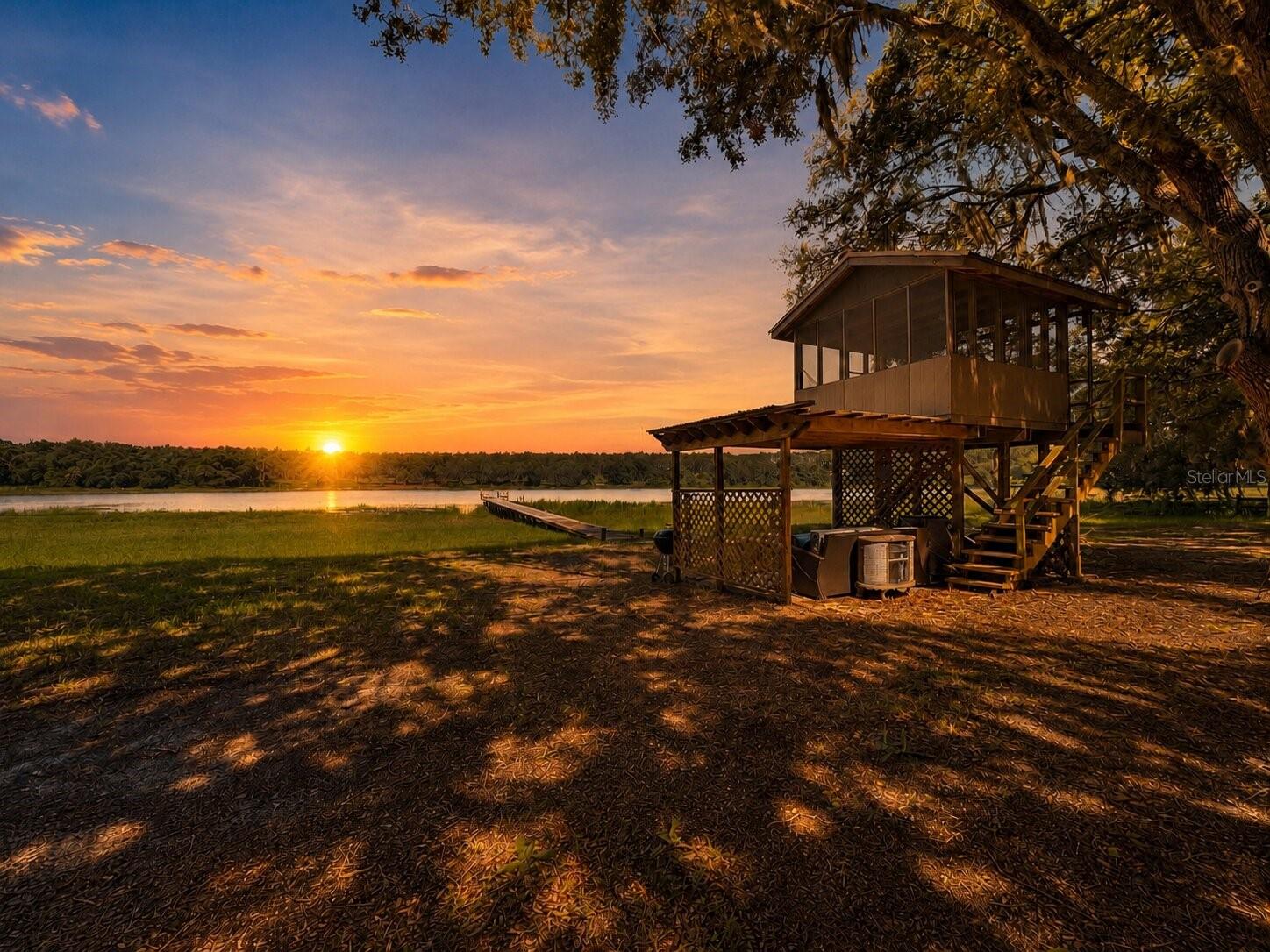 Welcome to your private Old Florida waterfront retreat on 3.51 acres with mature oak canopies, flowing Spanish moss, peaceful lake views, and abundant wildlife. This beautiful 3 bedroom, 2.5 bathroom home also features an additional 2 bedroom, 1 bathroom in-law suite with its own interior and exterior access, making it ideal for extended family, guests, or flexible living. Perfectly positioned to capture stunning sunsets over the private lake, the home offers a recently replaced dock with a sitting area, great for fishing, kayaking, canoeing, or enjoying a small boat while catching bass and bluegill. Inside, you’ll find an open floor plan with tile and luxury vinyl plank flooring throughout, no carpet, a large lakefront living area, spacious dining area, and a large kitchen with newer stainless steel appliances. The primary bedroom offers beautiful lake views, two large closets including a walk-in, and an updated bathroom with quartz double vanity, soaking tub, and shower combo. The guest bath has also been tastefully updated with a quartz vanity and tiled shower. The rear bonus area, currently used as two office spaces, offers incredible lake views and endless possibilities. Outside, enjoy a charming country front porch, elevated screened patio near the lake, covered paver patio, chicken coop, detached workshop, shed, deck with pergola-style roof, and heated above-ground pool. A whole-home 22kW generator with a 500-gallon propane tank adds peace of mind during storms. Less than 15 minutes from shopping, groceries, The Villages, and nearby local favorites like Eaton’s Beach, with Nelson’s Fish Camp and the Ocklawaha River boat ramp about 5 minutes away and Lake Weir’s Hope Boat Ramp less than 10 minutes away, this property is a dream for outdoor and Florida nature enthusiasts.