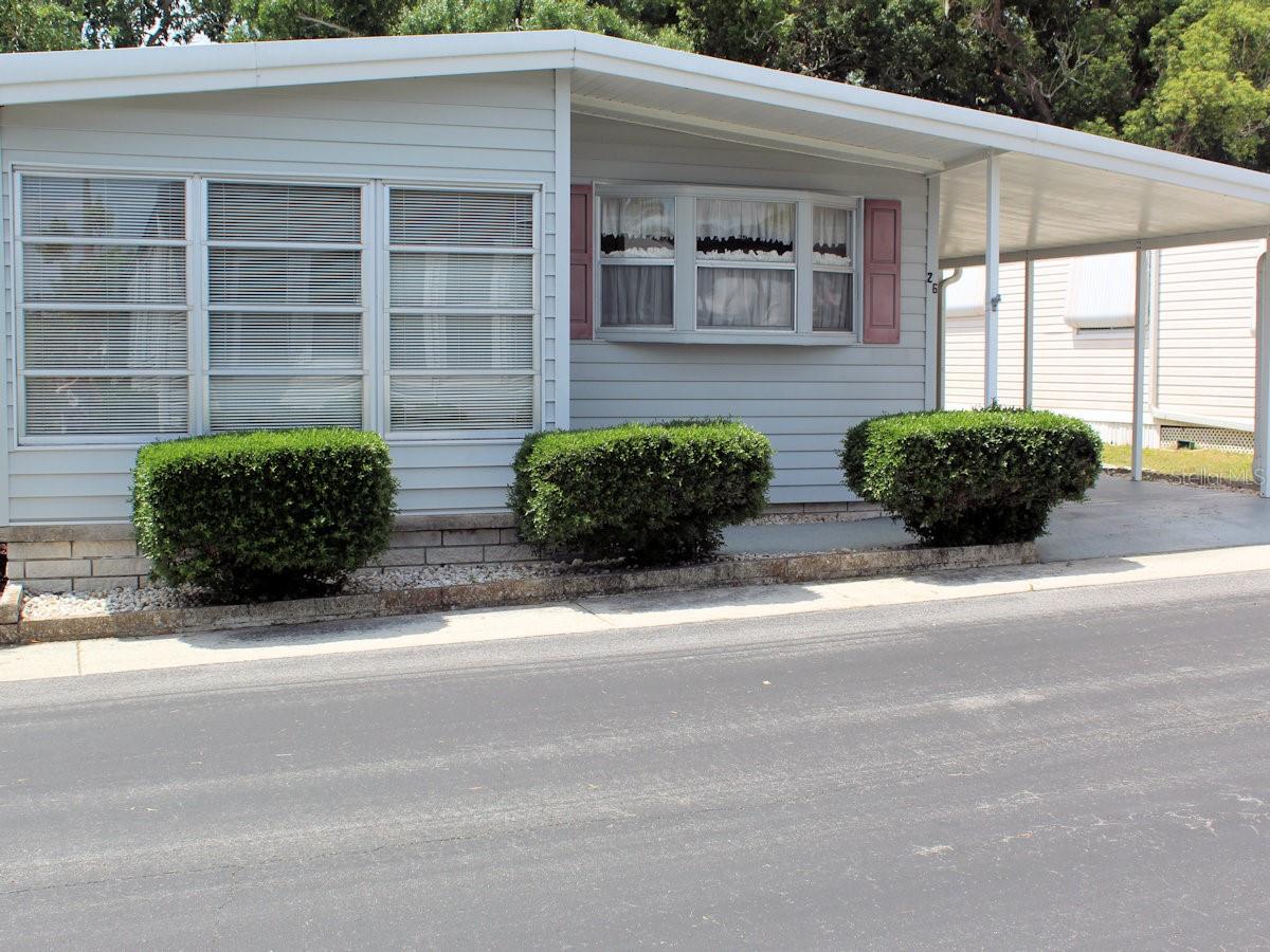 Here is the perfect pet location within the protective confines of Palm Hill Mobile Home Park, a 55+ community where each day feels like a vacation. This charming two bed, two bath manufactured home boasts a generous screened porch overlooking an expansive backyard.  What a perfect spot for you and your furry friend to enjoy restful days.  From golf outings, tennis, pickleball, bocce ball, shuffleboard, pools, jacuzzies, to clubhouse dances, there are many opportunities to make new friends. The community has one reasonable monthly fee of $594 which includes water, trash removal, lawn care, cable and internet. The front kitchen is well laid out and has front bay windows, refaced cabinets, quartz counter tops, updated sink and faucet, range, overhead microwave, refrigerator and dishwasher.  One of the countertops has plenty of room for quick lunches or snacks. There are ample upper and lower cabinet space and an additional storage cabinet.  Behind the kitchen is the sit-down dining room.  Floors here and throughout most of the home are laminate with plywood sub floors.  Most of the furniture will stay for the new owners. Across from the dining area is the living room.  Windows on either side of the living area have been updated and are double pane. Decorative molding throughout the interior gives a finished touch.  French doors lead to the front bonus family room with tile floors. Front windows and an exit door make it easy to visit neighbors. The primary bedroom is situated in the back.  This is attractively laid out with two generous size closets, attractive Haverty furniture, and an additional closet leading into the ensuite bath area.  This special bedroom is open to its own private suite which could also be used as a den area.  French doors lead to the exceptional enclosed screen room with its superb private backyard beyond.  The smaller guest bedroom is nearer to the living area and has adequate closet space.  Both baths have tile floors.  The ensuite has a large counter vanity area and a door leading to the toilet and shower while the guest bath has a tub with shower. This well laid out pet area home is move -in ready.  Most furniture will stay except for a Grandfather clock and special wall hangings. Light siding, front windows framed by manicured bushes and side trimmings along the carport emphasize the exterior.  The carport posts are updated and there is an attractive decorative kitchen door.  The home, shed and carport have an AMS roof over.  At the end of the carport there is a door leading into the utility shed. This area is divided into two sections with the first part being a storage space and beyond an opening leading to the space with washer, dryer, and soaking sink.  Plenty of space here.  Note also there is a door from the screened room leading inside to the shed. A three-ton air conditioner was installed in 2024. To see this fine property please call for a quick appointment before it is gone.  A share is included in the price.