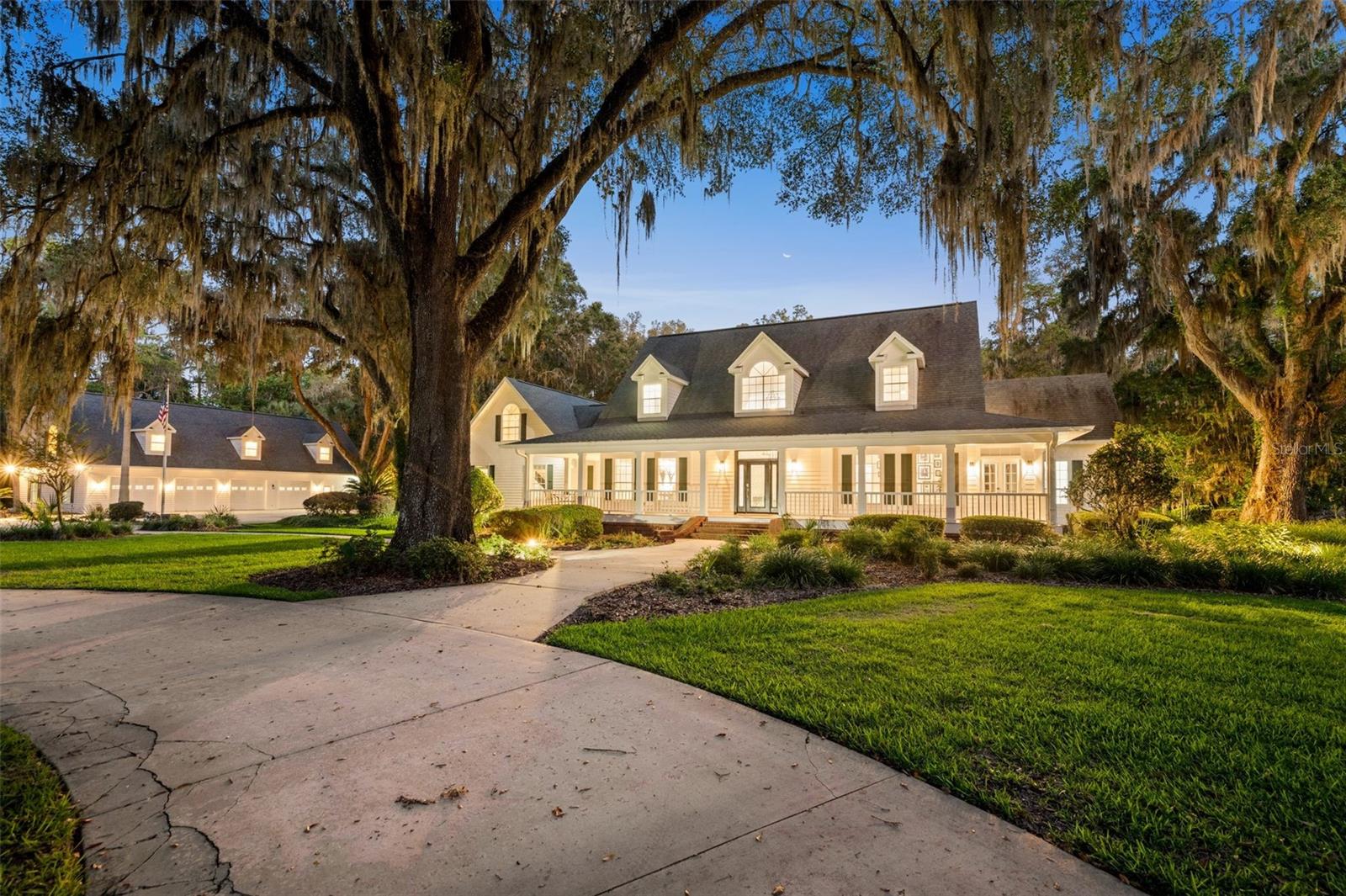 5 ACRES | GUEST HOUSE | 7-CAR GARAGE + WORKSHOP | PARTY BARN | BACKS TO 7,000+ ACRE STATE PARK
In a world that feels increasingly crowded, homes like this have become exceptionally rare.
Tucked behind a private electric gate and surrounded by five fully fenced acres, this estate offers something that’s nearly impossible to recreate: complete privacy, towering centuries-old oak trees, and direct access to more than 7,000 acres of protected state land. As you make your way down the circular drive, you’ll immediately notice the scale and intention behind every aspect of the estate. The magazine worthy main residence was designed for both everyday living and large-scale entertaining. As you walk up the steps of the wrap around front porch and through the front door, you are greeted by soaring two-story ceilings, herringbone tile floors, and a grand staircase. To the right, is a spacious study with private access to the porch, and an adjacent full bathroom. To the left, a formal dining room connected to the kitchen by way of a bar and walk in pantry. Beyond the staircase, the family room is framed by walls of glass overlooking the pool and preserve, while a double-sided fireplace connects the living spaces to the updated kitchen featuring quartz countertops, premium stainless appliances, and an oversized island. Downstairs, you’ll also find a stunning primary retreat- double doors open to a king sized bedroom, with a sitting area, electric fireplace, and double doors leading to the screen enclosed back porch. A modern barn door opens to the completely reimagined primary bath featuring soaring cathedral ceilings, dual vanities, a dedicated makeup station, a Toto-equipped water closet, a frameless shower, a jetted soaking tub overlooking a centuries-old oak, and an extraordinary walk-in closet. Upstairs are two bedrooms, one with a private office space, both with multiple closets, and a full bath. Just past the kitchen is a walk-in laundry room and access to the 3 car attached garage with its own full bath (doubling as a pool bath), and a staircase leading to a large bonus room, creating a flexible space for a media room, gym, or additional guest accommodations. For car collectors, hobbyists, business owners, or multi-generational families, the detached garage is a standout feature all on it’s own. The lower level offers four oversized garage bays, a full workshop with extensive storage and pendant lighting, a private office, full bathroom, and a full secondary kitchen. Above, you’ll find a beautifully finished one-bedroom apartment featuring another full kitchen, living room, walk-in closet, laundry room, bedroom, and full bath- perfect for guests, extended family, or an on-site caretaker. Step outside and you’ll discover why this property is truly one-of-a-kind. Outside, a resort-style lap pool and fire pit overlook the preserve, while a gazebo, meditation garden with a swinging bench, party barn, and extensive utility storage create endless opportunities to entertain, relax, and enjoy the outdoors. There’s even a covered RV parking area with 50 Amp service, water, and septic. Located in a horse-friendly community, this is a property where you can spend your mornings watching deer wander, and your evenings gathered around the fire with family and friends. Opportunities to own a private estate of this scale, with this level of infrastructure, are becoming increasingly difficult to find. Welcome to Enchanted Oaks.