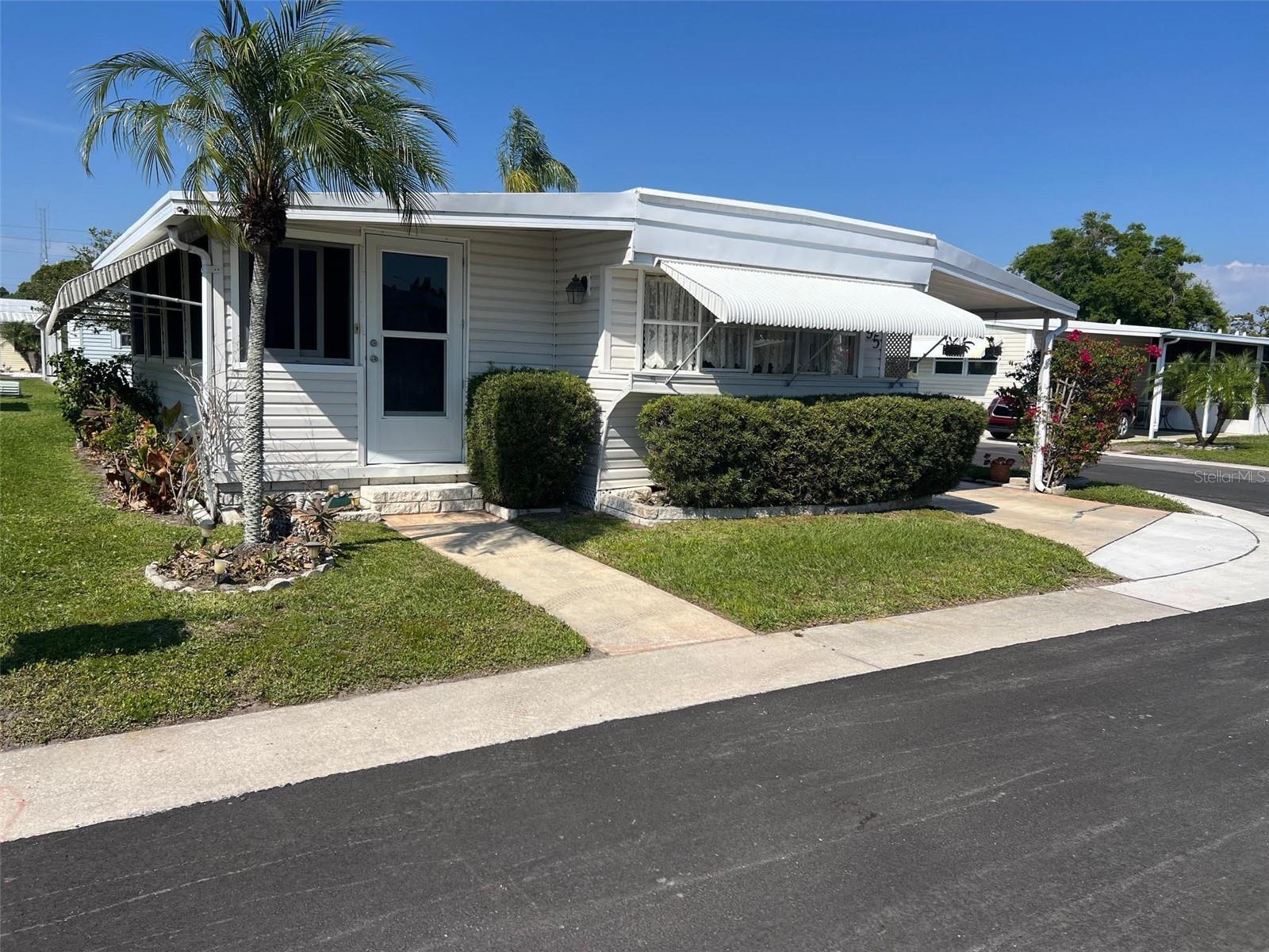 Tucked within the welcoming setting of Bel Aire Mobile Village, this newly listed 2-bedroom, 1-bath home offers a wonderful opportunity for those with a vision to make it their own. Positioned on a desirable corner lot, the property enjoys added space and a pleasant sense of openness, while the home itself is ready for a touch of TLC to truly shine. Life here is all about simplicity and connection, with one of the most budget-friendly monthly maintenance fees in Pinellas County at just $235, conveniently covering water, sewer, garbage, and lawn care—allowing you to enjoy more and worry less. This quiet 55+ community welcomes one small pet and features charming sidewalks perfect for strolls, friendly chats with neighbors, and staying active. Residents also enjoy a clubhouse that serves as a social hub, along with shuffleboard courts and a refreshing swimming pool, creating a relaxed yet engaging lifestyle that makes this hidden gem well worth a closer look.
INTERIOR:
Join us inside and review the prospects of a space full of potential that will make you want to call this home your own! This partly furnished interior offers laminate flooring throughout most of the home, complemented by paneled walls and updated windows that invite in natural light. Central heat and air, updated in 2021, provide seasonal comfort. The raised Florida room is a versatile entry point, complete with washer and dryer hookups and access through two newer sliding doors—one leading directly into the kitchen, where a stainless steel appliance suite including a range, oven, refrigerator with ice maker, microwave, and dishwasher awaits, along with space for a table to create a welcoming eat-in area. The second slider opens into a cozy living room with soft carpeting and enough room to comfortably entertain guests. A generously sized guest bedroom offers flexibility for visitors or can easily serve as a home office, craft room, or fitness area, with a closet for added storage. The main bathroom features a single sink vanity, durable vinyl flooring, and a tub/shower combination for added practicality. Completing the home is a bright, spacious primary bedroom with a wall-to-wall closet, offering ample storage to keep everything neatly organized.
EXTERIOR:
From the moment you arrive, the exterior sets the stage for easy Florida living with features that invite you to relax. Vinyl siding pairs with a roof over for added protection, clean landscaping complements the home’s appeal, while awnings enhance both style and function. A long carport offers ample covered parking and includes a welcoming sitting area—perfect for enjoying a morning coffee or unwinding in the evening breeze. Practical upgrades such as a newer breaker box and a 40-gallon water heater installed in 2020 add peace of mind, and the shed provides valuable extra storage space. Priced attractively at $74,900, including the share, this property leaves plenty of room to add your personal touches and truly make it your own—the possibilities here are truly endless!