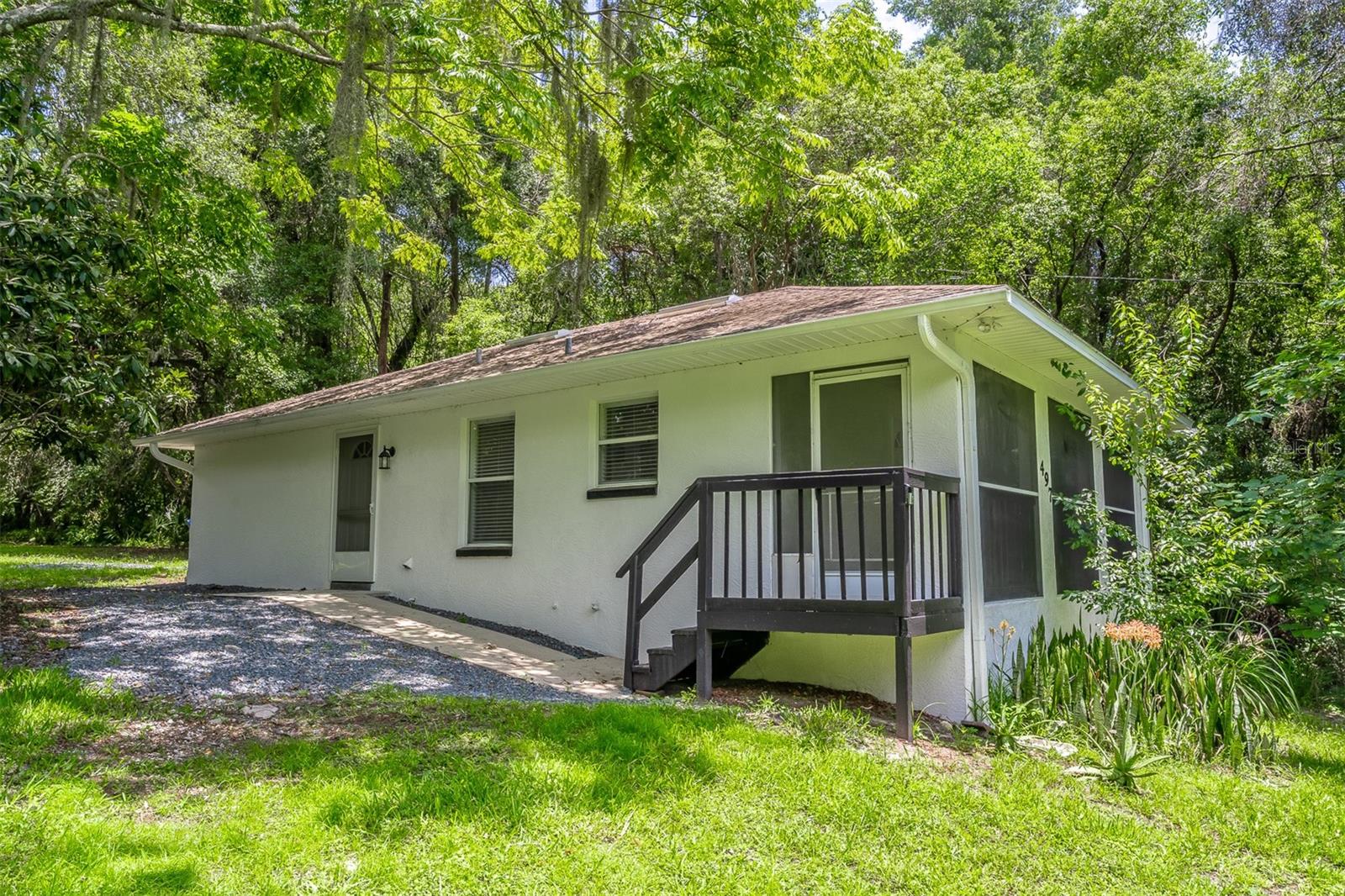 If you've been searching for a place where you can finally spread out, enjoy nature, and escape the feeling of living on top of your neighbors, this is the home you've been waiting for. Hidden beneath a canopy of mature trees on ½ acre, this beautifully renovated block home feels like your own private retreat. As you turn onto the driveway, the landscape begins to change. Towering trees create a natural privacy screen, the home sits comfortably back from the road, and before you know it, the outside world simply fades away. Completely move-in ready, this 2-bedroom, 1-bath home features fresh interior and exterior paint, luxury vinyl flooring throughout, a beautifully updated kitchen with new countertops and brand-new stainless steel appliances, and a spacious, fully renovated bathroom with a custom tiled shower, new vanity, and linen closet. The interior laundry room and tankless water heater provide additional storage and everyday convenience.Start your mornings on the screened front porch overlooking nothing but lush greenery, listening to birds instead of traffic. It's the kind of setting that instantly helps you slow down and relax. Outside is where this property truly shines. Whether you've dreamed of building a fire pit, planting gardens, adding an accessory dwelling unit (ADU), or simply having room for your boat, RV, ATV, jet skis, or workshop, this property gives you the freedom to create the lifestyle you want. No HOA means no unnecessary restrictions. Affordable properties with this much privacy, usable land, and thoughtful updates rarely become available. Whether you're buying your first home, downsizing, investing, or simply looking for your own peaceful retreat, this property offers an incredible opportunity to enjoy a lifestyle that's becoming increasingly difficult to find.