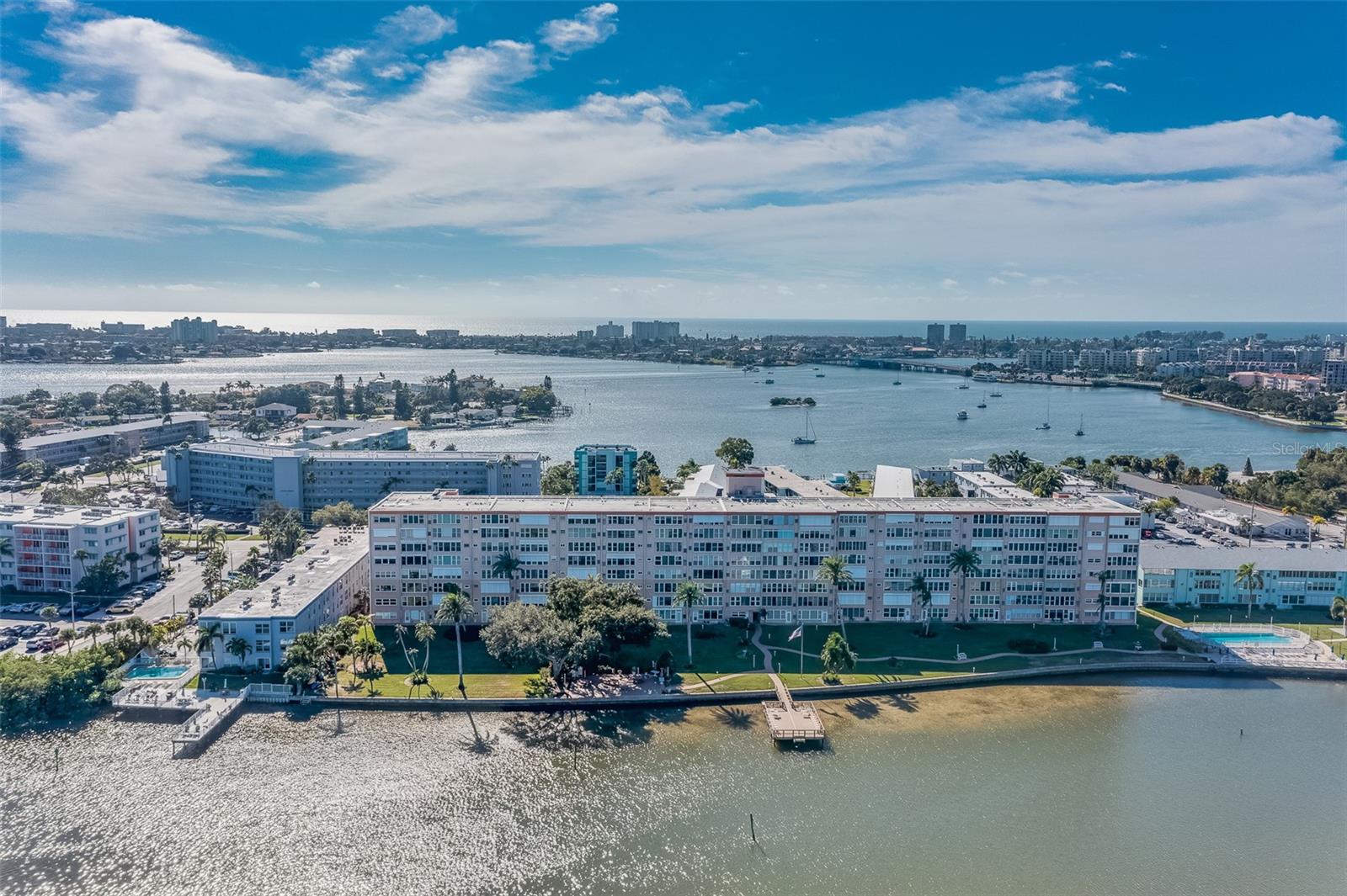 One or more photo(s) has been virtually staged. This is waterfront living at its finest.  With 1250 square feet, two bedrooms and two baths, this waterfront paradise is move in ready.  With the building's new roof last year, the HOA fees were just reduced to $658 and all milestones were completed years ago.  This unit has an incredible walkout waterfront view on the first floor in a garden like waterfront setting. The community has a heated pool and access to a second pool across the street, along with many fun amenities.  There are various clubs and gatherings opportunities, Exercise room, clubhouse, Kayak launch and storage, fishing pier, cornhole, gas grills, library and card room. The community provides gas water heating and cooking as well as cable/Internet package included in your HOA fees. Each unit has access to a large storage closet with plenty of space for your bikes.  This unit includes flood barrier systems on the front and rear doors for extra protection.  The primary bedroom has a sliding door to let in the waterfront view from the Florida Room for very open feel.  The bathrooms are both updated as well and include safety bars.  The kitchen is gorgeous, with newer appliances and custom grade wood cabinets, the chef will feel right at home. 2022 HVAC is regularly serviced.  The Shorecrest building is solid concrete, not frame, and this unit is very close to the dedicated parking spot #2 and first floor laundry room. In unit laundry is possible if you wanted to change out the dishwasher. The monthly newsletter will give you plenty of opportunities to connect with the friendly residents here. This island community is very walkable and centrally located to everything you are looking for. 1.5 miles to St Pete Beach, .3 miles to the Orange Groves winery, 1.5 miles to shopping, dining, and Bowling. Downtown St Pete is 8 miles driving, or take the sun runner to and from downtown or the beaches.  The building is walking distance (.5 mile) to Pasadena Marina, so bring your boat and enjoy waterfront beauty and convenience at a great price. ***Room sizes are approximate please see floor plan.
