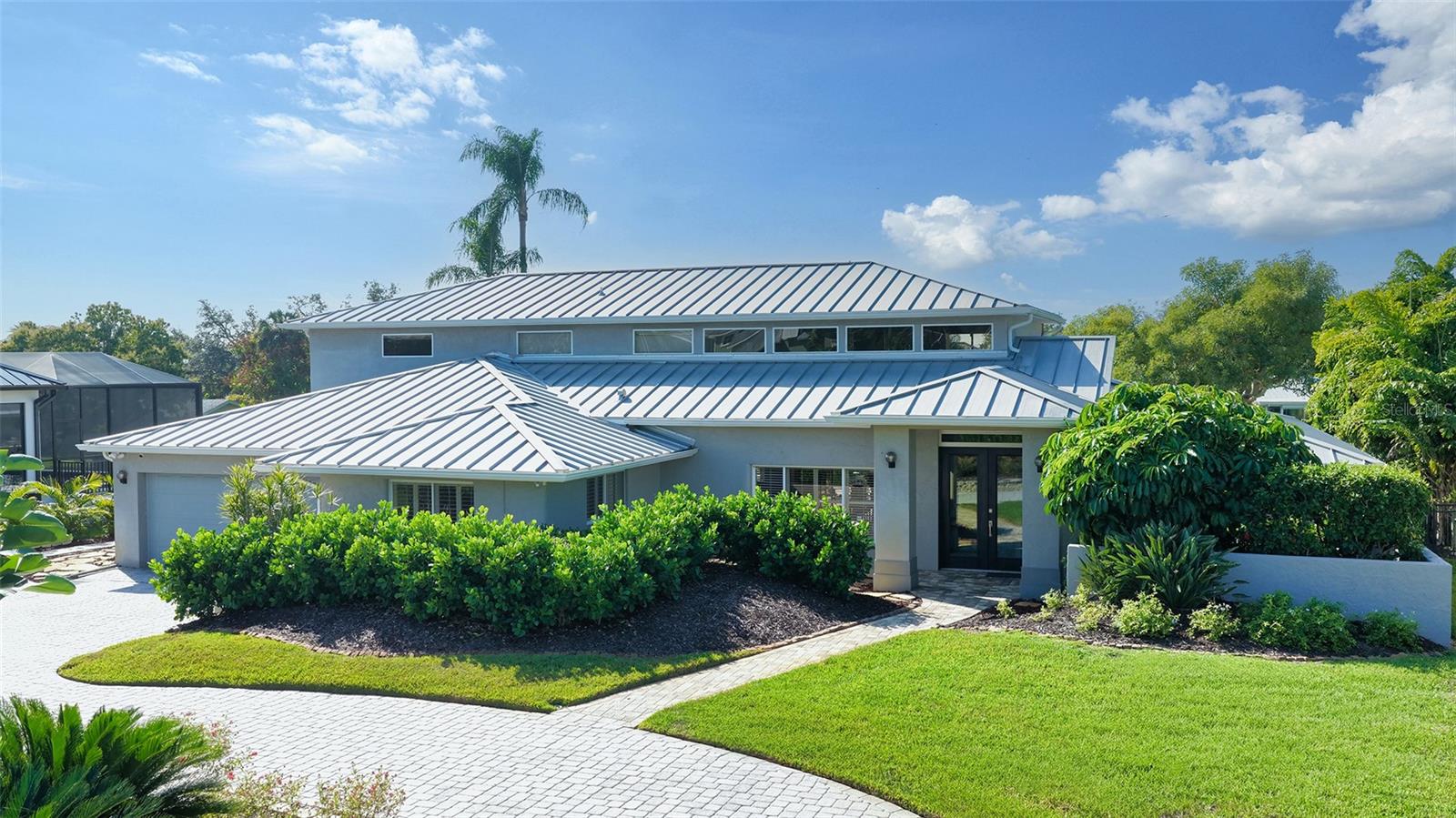 Nestled within the secure, mainland West-of-Trail enclave of Coral Cove, this elevated 2-story waterfront residence offers refined coastal living on a generous 17,000+ square-foot canal-front homesite with direct access to the Intracoastal Waterway. Positioned in an X flood zone and exhibiting exceptional resilience, the property sustained no storm impact and features a standing-seam metal roof, mature landscaping, and a well servicing the irrigation system. A brick-paver circular drive introduces a striking double-door entrance, opening to a light-filled interior defined by soaring volume ceilings, clerestory windows, and an airy, sun-washed ambiance. The welcoming foyer flows into a spacious living and dining composition designed for both intimate and large gatherings. At the heart of the home, the centrally placed kitchen features expansive sightlines, abundant cabinetry, and a seamless aquarium-glass breakfast retreat overlooking tranquil water vistas. Adjacent, a large 21x24 family room with bar, wine refrigerator, sink and fireplace extends effortlessly outdoors, creating a harmonious connection between interior comfort and open-air relaxation. The main living level has a second main bedroom plus 2 guest rooms. One bedroom is currently designed as a study. A stairway ascends to an open gallery walkway leading to an extraordinary 25x18 owner’s sanctuary. This upper-level retreat showcases a spa-inspired bath, custom-tailored walk-in wardrobe, plus a dedicated exercise studio or nursery. Enjoy private access to an upper sun deck overlooking the water. Outdoor living is truly exceptional, with an expansive entertainment environment featuring a swim-spa, screened lounging deck, additional open-air terrace, and fully fenced backyard ideal for pets or play. The Trex dock is engineered to accommodate a large boat, offering easy access to the bay and beyond. Coral Cove residents enjoy exclusive use of a private two-acre waterfront park and community boat ramp, fostering a close-knit, serene atmosphere. Peaceful surroundings pair beautifully with remarkable convenience to shopping, dining, and cultural attractions, while the powder-white sands of Siesta Key Beach—ranked the nation’s finest—are just minutes away. A rare blend of security, scale, natural light, and waterfront sophistication, this Coral Cove offering delivers an elevated coastal lifestyle without compromise.