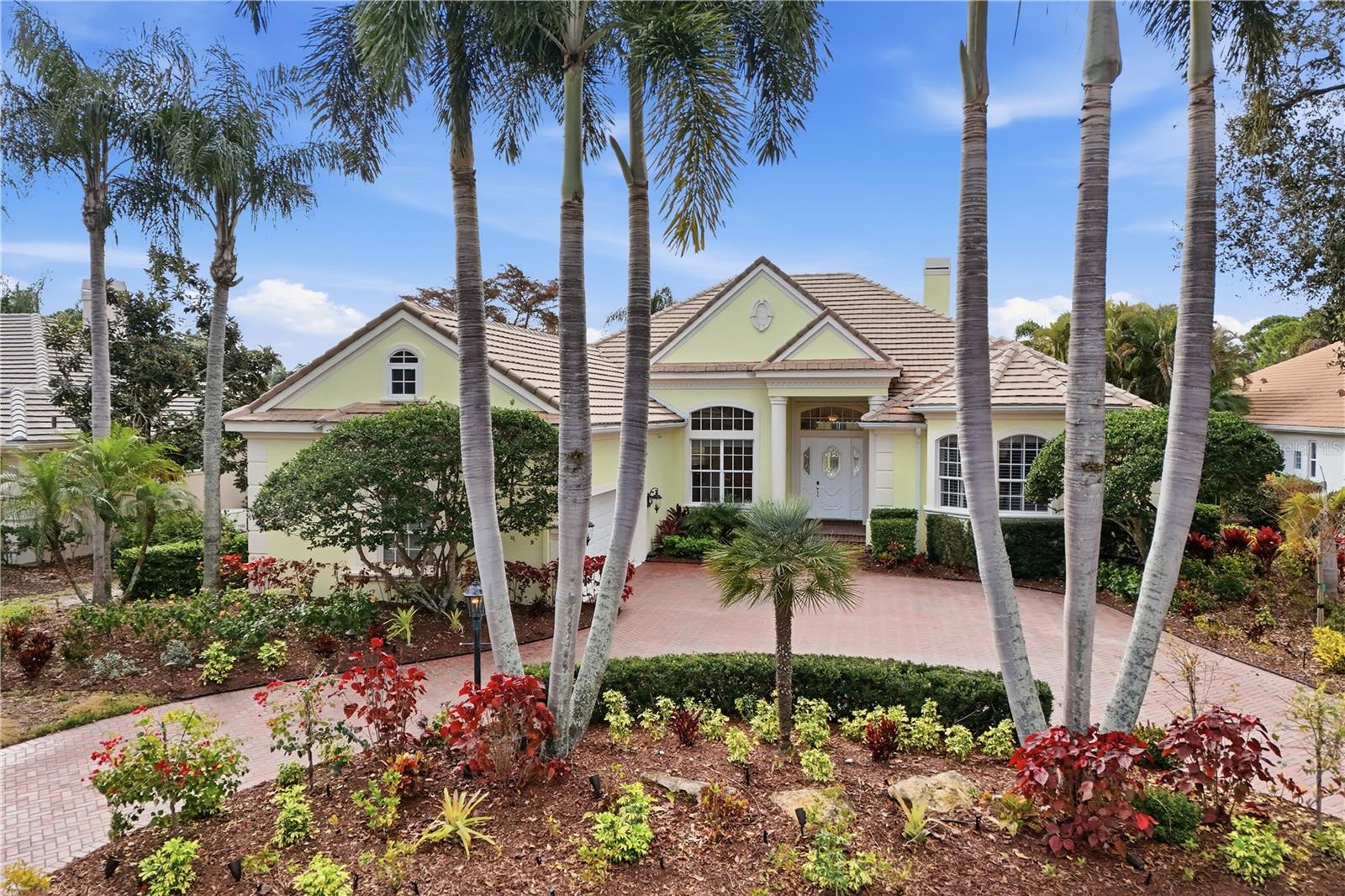 Experience refined Florida living in this stunning estate home located in the highly sought-after University Park Country Club. Now offered at an exceptional new price of $1,490,000, this residence presents an incredible opportunity to own over 4,200 square feet of elegant living space in one of the area’s premier golf communities.
A gracious arrival begins with a circular brick paver drive and an oversized two-car garage with a separate golf cart bay. Inside, elegant formal spaces set the tone: the living room with fireplace and the formal dining room both showcase crown molding and soaring 12-foot ceilings, while walls of sliders open to the expansive pool terrace and sparkling water views.
The heart of the home is the open family room, seamlessly connected to the kitchen and sunlit breakfast nook, creating a natural gathering place for everyday living and entertaining. A beautifully appointed office is positioned toward the rear of the residence, offering custom built-in desk and bookcases along with private sliders to the pool terrace—an inspiring work-from-home setting that blends productivity with resort-style surroundings.
The primary suite is a true retreat, complete with a tranquil sitting area and private sliders opening to the pool terrace. Dual walk-in closets and a dedicated dressing area provide exceptional storage and function. The spa-inspired primary baths has individual vanities, a shared dual-entry shower, and a luxurious soaking tub—creating a private sanctuary designed for both relaxation and ease.

Two additional guest bedrooms are complemented by two well-appointed full baths, while a stylish powder room serves visitors. A spacious upstairs bonus room—ideal for a home theater, game room,  or possible 4th bedroom  with large walk-in closet—adds even more flexibility for family and guests.
Outdoor living is nothing short of spectacular. An oversized pool deck surrounds the heated pool and spa, complemented by a fully equipped outdoor kitchen—all overlooking tranquil lake vistas. This is a home designed to host unforgettable evenings with friends and relaxed weekends with family.
Designed for both beauty and assurance, the home includes impact windows, hurricane shutters, and a generator so owners can enjoy refined living with complete peace of mind.
Residents of University Park Country Club enjoy a lifestyle that blends luxury, recreation, and connection. Amenities include 27 holes of championship golf, tennis, pickleball, croquet, fitness and wellness, and an active calendar of dining and social events. Miles of scenic sidewalks and winding paths link 32 distinctive neighborhoods, creating a welcoming setting for walking, biking, and getting to know your neighbors. With vibrant clubs, special interest groups, and community traditions, it’s easy to feel at home while enjoying the privacy of a beautifully planned environment.

Luxury, privacy, and community—perfectly balanced.