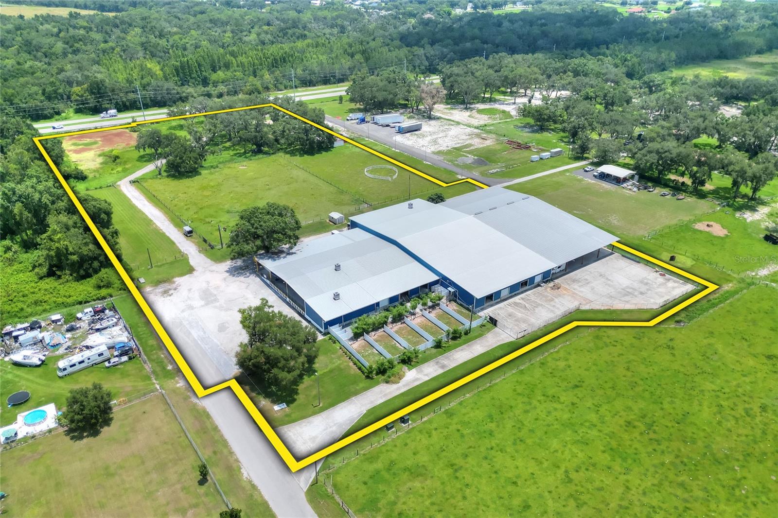 Positioned on County Line Road and E Trapnell Road in Plant City, this 53,032± sf warehouse sits on 8.93± acres in the heart of one of Central Florida’s fastest-growing industrial corridors. The property offers prime frontage with a valuable median break for full access and is located just 4.5 miles from the I-4 interchange, making it an ideal site for current use and future growth. Currently zoned AS-0.4 with a future land use of AE, the site supports a variety of approvable uses and offers strong long-term upside as the corridor continues to expand.
The facility features approximately 53,032sf under roof, including 30,432sf of enclosed space, 432sf office, a 9,000sf covered dock area, and a 13,168sf covered concrete pad – ideal for outdoor work or covered storage. Inside, a 3,600 square foot mezzanine provides additional functional space for storage. With 13 loading docks and 3-phase power, the layout supports a wide range of operational needs and offers a flexible configuration for most users. In addition to its County Line Road access, the property features an entrance off E Trapnell Road, improving circulation and site flexibility. An additional 5+ acres of vacant land is included in the sale, offering room for outdoor use, expansion, or future development. This is a rare opportunity to acquire a versatile facility in a high-growth corridor with immediate utility and long-term investment potential.