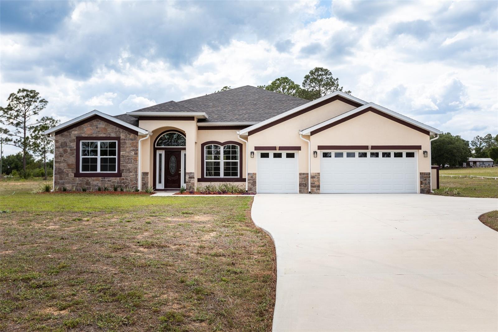 Experience luxury living on 1.3 acres with this one-of-a-kind custom-built residence showcasing exceptional craftsmanship and meticulous attention to detail throughout.  Home features soaring ceilings, elegant tile flooring in every room, and refined trim and ceiling accents that elevate the home’s design. Offering four spacious bedrooms, three full bathrooms, and a convenient half bath for guests.  This property combines comfort with high-end finishes and superior quality of construction. One of the full bathrooms is designed as a Jack-and-Jill, providing both functionality and privacy. The home includes solid block construction and energy-efficient windows for durability and efficiency, along with custom closets featuring solid wood shelving throughout—no ventilated wire shelving. The exterior impresses with a beautiful combination of stucco and gorgeous stonework, creating striking curb appeal. The expansive acreage offers ample space to enjoy the Florida lifestyle, with room for a pole barn, a pool, or additional outdoor living enhancements. A generous three-stall garage provides ample space for vehicles and storage, completing this remarkable home that blends luxury, functionality, and lasting value. The seller is offering a bonus new washer and dryer.