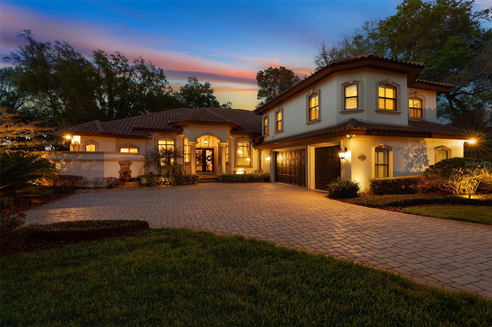 Discover an unparalleled level of luxury at 7341 Bella Foresta Place, an extraordinary custom estate on a premier one-acre homesite within the private, gated enclave of Bella Foresta. This residence combines exceptional craftsmanship, robust mechanical systems, and resort-style living to create a sanctuary of sophistication and privacy.
The journey begins at the grand entrance, where massive cast stone columns frame custom mahogany-toned double doors with intricate wrought-iron scrollwork. Guests enter a grand foyer showcasing a dramatic ceiling and timeless travertine flooring throughout the main living areas. The formal living room serves as a refined greeting space with a custom coffered ceiling, natural gas fireplace with a decorative tile mantle, and bay windows with private access to the lanai oasis. An executive home office features glass French doors and a double-tray ceiling, while the formal dining room is elegantly appointed with recessed accent lighting. The expansive family room showcases 10-foot pocket sliding glass doors that disappear to create a seamless transition to the pool courtyard.
The chef's kitchen is designed for grand-scale entertaining, boasting 42" custom two-tone dovetail cabinetry, a mosaic tile backsplash, and granite countertops. A central prep island and massive wraparound bar complement the natural gas cooktop with custom range hood, pot filler, and stainless-steel appliances while the light-filled breakfast nook features panoramic bay windows overlooking the manicured grounds. The owner's retreat offers a serene sanctuary with private lanai access and a spa-inspired bath featuring travertine floors, split granite vanities, and a massive tile walk-in shower with vertical mosaic accents. Dual "his and hers" walk-in closets feature full custom built-in organization systems.
The thoughtful layout includes a private downstairs guest wing addition (2012) featuring a guest suite with double-door entry and a high-end en-suite bath. The upper level provides exceptional flexibility with a massive bonus room--ideal for a theater or game room--alongside an additional guest bedroom with a private en-suite bath. A dedicated home gym with tray ceilings and direct pool access ensures a seamless fitness lifestyle.
Step outside to a spectacular resort-style outdoor living space. The expansive paver lanai offers multiple covered seating areas and a gas-heated chlorine pool and spa (equipment updated 2022) featuring a modern sculptural waterfall ledge and outdoor shower. Beyond the courtyard, the sprawling one-acre estate offers exceptional privacy and manicured lawn space maintained by a city reclaimed irrigation system.
The oversized 3-car garage features 8-foot insulated doors and freshly painted floors, providing ample space for vehicles and storage. Upgrades include:

-Whole-house Generac generator with automatic transfer switch
-Two gas tankless water heaters (installed 2021)
-Four-zone HVAC system for precision climate control
-2015 Tile Roof for lasting durability and curb appeal
-Natural gas fireplace with custom tile mantle
-Built-in mudroom bench and transition hallway storage
-Full appliance package included
-City reclaimed water irrigation system

7341 Bella Foresta Place is a rare opportunity to own a premier custom luxury estate where craftsmanship, technology, and resort-style living converge.