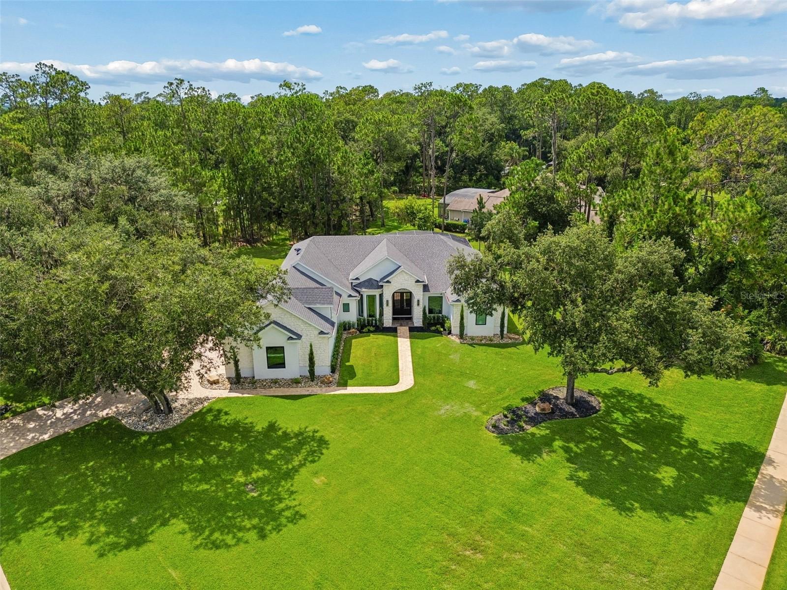 Stunning 4-bedroom, 3-bathroom luxury estate — fully renovated from the studs — in the highly sought-after Live Oak Estates community in the Lake Nona area, set on a 1.18-acre corner lot among custom homes on large private properties. This 2003-built residence has undergone a complete down-to-the-studs transformation, with the original compartmentalized floor plan reconfigured into an open-concept layout that maximizes flow and natural light. Highlights include a custom-built staircase with integrated in-wall LED lighting, all-new custom picture-frame windows throughout, an oversized entrance window system, a custom living room picture-frame window, and hurricane-rated impact windows and doors.

The chef's kitchen is a true showstopper, featuring custom floor-to-ceiling cabinetry, premium quartz countertops throughout, and an oversized 136" x 56" mitered-edge quartz island with additional built-in storage. A high-end ZLINE appliance package, including a 36-inch ZLINE cooktop, anchors the space, complemented by modern plumbing fixtures and sink upgrades. Every wall has been retextured from the original knockdown finish to a fine orange peel finish, ceilings refinished, and the entire interior freshly repainted. All lighting fixtures have been replaced with modern designer fixtures, all plumbing fixtures replaced throughout the home, and modern linear HVAC vents and registers installed.

The primary suite offers a true spa-style retreat with a dual walk-in shower configuration, a freestanding soaking tub, all-new plumbing, custom vanities with mitered-edge quartz countertops matching the kitchen, and large-format 40" x 40" tile extending continuously from floor to ceiling behind a custom frameless glass shower enclosure. A heated toilet completes the primary bath. The fully renovated pool bathroom features a custom vanity and cabinetry, mitered-edge quartz countertop, custom walk-in shower, new plumbing fixtures, and a heated toilet, while the additional bathroom also includes a heated toilet, updated fixtures, and modern plumbing and hardware upgrades.

The custom laundry room mirrors the kitchen's design with matching cabinetry, mitered-edge quartz countertops, a utility sink, custom storage solutions, and a new washer and dryer. Large-format tile has been installed throughout the main living areas, the staircase fully renovated with integrated LED lighting, and new carpet installed in the bonus/media room. The home also features a custom in-house integrated technology system with lighting and technology upgrades throughout.

Outdoor and site improvements are equally impressive, including a completely new irrigation system — a new Rain Bird system with 7 new valves — supplied by a brand-new premium bedrock well installed specifically for irrigation water supply. The pool area, outdoor entertainment space, and lanai have all been upgraded, and the grounds have been transformed with removal of overgrown vegetation, tree removal and stump grinding, and an entirely new landscape design, resulting in true estate-style curb appeal beneath mature oak trees. The property also includes a 3-car garage and a pool solar panel system.