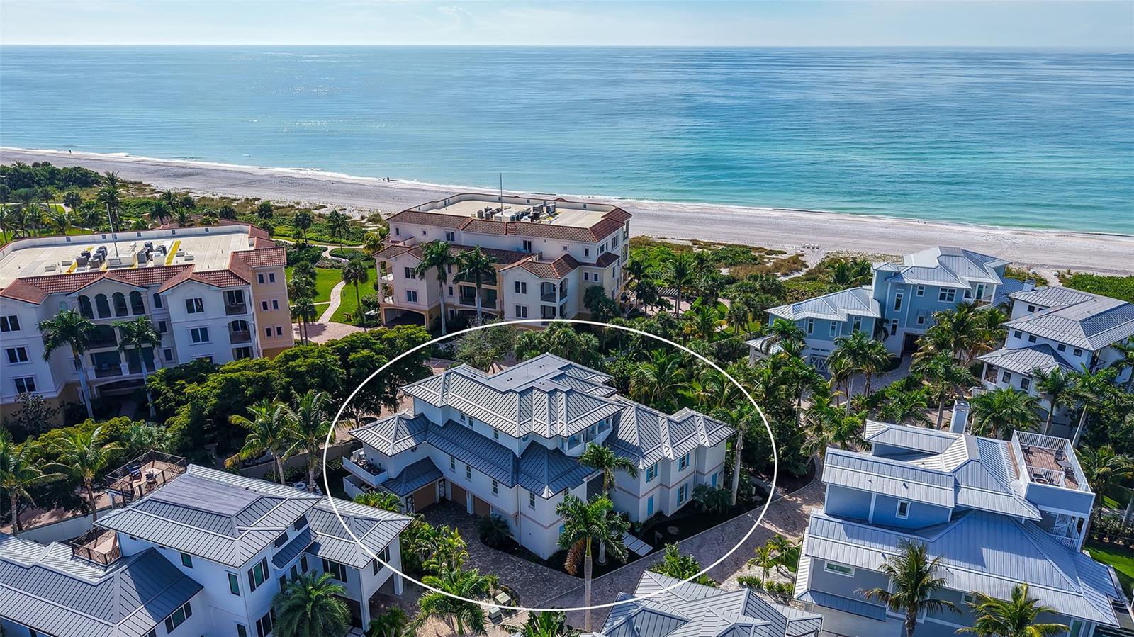 Designed by award-winning architect, John Cooney, and built by Sarasota’s premier coastal homebuilder, Perrone Construction, this mid-Key classic is simply among Longboat Key’s finest homes.
Walk in to this fully furnished home which is steps from the beach and with expansive Gulf and Bay views, this masterpiece offers more than 4300 square feet of refined interiors on the main living floors together with multiple large lanais and balconies.  A beautiful foyer, large family room, and home gym are featured on the ground floor, along with an oversized three-car garage and storage room.
The quality of the home’s design and construction are matched by the charm of the interior finishes and amenities.  The living areas incorporate beautiful ceiling elevations, along with custom wide-plank hardwood, Italian porcelain tile, and custom plantation shutters and drapes.  The Great Room flows into the chef’s kitchen which features custom cabinetry, quartz countertops, Wolf and SubZero appliances, and a temperature-controlled 275 bottle wine room.  Designed for easy entertaining, the Great Room opens onto a large lanai with its gas fireplace and grill, and gorgeous Gulf and sunset views.  Adjoining the kitchen is a perfect dining room with its own balcony and Gulf views, as well as a large family office/bonus room with custom cabinetry and bookshelves.  The Lutron system controls both the lighting and the custom drapes and shades.  The home’s elegant chandeliers and sconces bathe its interior with gracious warmth.
The beautiful master suite on the main floor includes a bedroom cathedral ceiling and access to the outdoor lanai.  The master bath features custom cabinetry, porcelain tile, a large steam shower, and is plumbed for a master bathtub.
Three spacious guest suites, a gathering lounge, and balconies with Gulf views are found on the second living floor.  A private elevator connects all levels.
Both the home and exterior grounds are designed for year-round, low-maintenance living.  An extensive landscape refresh in 2023 included new turf and lighting, an outdoor shower, and a great fire pit area for entertaining.  Lush landscaping and a tranquil pool setting provide both screening and privacy.  The home features remote controlled screening and storm shutters, extensive use of Azek composite, and other low-maintenance materials, along with a gas generator, whole-house water filtration system, central vacuum, and much more.
With miles of pristine beach and bay to explore and with the abundant cultural, dining, and shopping amenities of Sarasota, St. Armand’s Circle, and Anna Maria Island nearby, this timeless home delivers the very best of Longboat Key living.