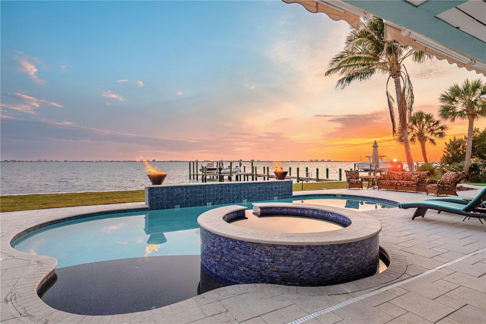 Imagine owning one of Sarasota Bay’s most exciting waterfront properties, where panoramic views, deep water access, and resort-style living create the kind of lifestyle people dream about but rarely find. Set on an oversized 2/3-acre lot with 172 feet of direct bay frontage, this fully renovated Sapphire Shores estate was redesigned for unforgettable entertaining and vibrant coastal living. Enjoy breathtaking panoramic views stretching across Sarasota Bay from Downtown city lights to Longboat Key, a 100-foot deep water dock with dual lifts 10,000 and 15,000 lbs, brand new seawall, resort-style pool and new spa, outdoor kitchen, multiple expansive decks, and a whole-home smart system with Sonos audio, Lutron lighting, Tesla solar power walls and charging, and security integration. Inside, the home offers five ensuite bedrooms, six-and-a-half baths, a designer kitchen with custom coffee bar, finished game room, luxurious primary suite, and walls of hurricane-rated glass that bring the water into nearly every space. With a brand new standing seam metal roof, updated systems throughout, 16-foot elevation, this property delivers the rare combination of luxury, boating lifestyle, privacy, and peace of mind. Close proximity to Downtown Sarasota, SRQ airport and only 8.4 Miles to IMG Academy. Waterfront homes like this rarely become available. Inquire with listing agent for a full list of improvements. Schedule your private showing today.