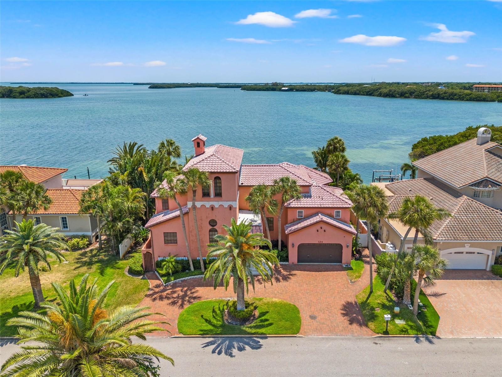 LOCATION! LOCATION! LOCATION! Open waterfront locations like this rarely come available on Tierra Verde. This stately Spanish Mediterranean waterfront pool estate is situated on one of the most desirable and well-known streets on the island, Sands Point Dr. This solid concrete block and steel-constructed residence is a fortress and is perfectly elevated on a pristine lot with lush private landscaping and 95’ of open turquoise waterfront. You’re sure to be mesmerized by the breathtaking panoramic open water views from several large private balconies overlooking the dazzling waters where Tampa Bay kisses the Gulf of Mexico underneath the Sunshine Skyway bridge. Amazing vistas from virtually every room include the Greenland Preserve and Fort De Soto. This is a boater’s paradise with a newer raised seawall and dock with water, power, a cleaning station, plus two large boat lifts and a tandem jet ski lift. You will have quick unobstructed access to the deep blue waters of Tampa Bay and the Gulf of Mexico right from your backyard. A few updates can easily make this your forever dream home! The home boasts (4) bedrooms, five (5) bathrooms, over 4,000 square feet of living space plus an additional 1,800 square feet of non-heated space on the lower level that’s perfect for storage, a gym, a game room, man cave or she shed. Other significant features include travertine and bamboo flooring throughout, high ceilings, plus two (2) primary ensuites, a first-level, and second-level owner’s retreat makes living here a true escape. The second-level primary bedroom includes a spa-like bath with sauna/steam room and a separate 12x15 dressing room with floor-to-ceiling closet organization. Off the first-level primary is a wrap-around terrace overlooking the private resort-style backyard perfect for entertaining guests. A formal and casual living area both offer views of the pool, the sparkling waterfront, and the tropical landscaping. In the kitchen, you’ll find granite counters, real wood cabinets, Thermador, Sub-Zero & Bosch appliances, plus another exceptional water view. Exit the kitchen and step into the great room with high ceilings, a large stone fireplace & doorways to a large travertine deck with stone balustrades overlooking the pool and sparkling waterfront views. Yes, water views unfold from nearly every room in the residence. Updated electrical, newer on-demand water heaters (2020), newer pool equipment, lightning rods, fresh paint, plus hook-ups for a Tesla EV charger and a Generac generator are some more recent updates you’ll enjoy. A circular driveway adds to the curb appeal. With a plethora of shops and restaurants at your fingertips on the island, you’ll never need to leave but should you want to, you are conveniently located just minutes from Fort De Soto, The Don Cesar, and St Pete’s number one beach, Pass-A-Grille Beach. You’re also only 15 minutes from vibrant Downtown St. Pete and 30 minutes to TPA. This is your rare opportunity to own a slice of waterfront paradise in the most desirable location on Tierra Verde. Call to schedule your private tour and make this oasis your forever home today.