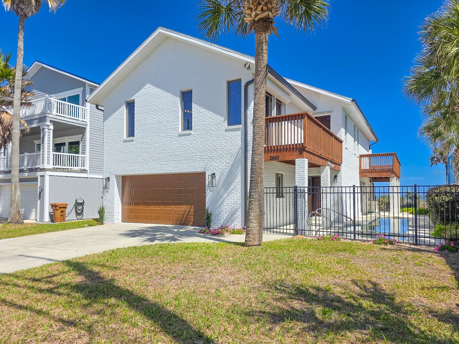Elegant Oceanfront Beach Home. Magnificent views! Direct Oceanfront lot across the street is included, and available for your own private walk over. Beach access is step away at the end of every city cross street with A1A. The exterior of this home features iconic architectural elements. Classic white painted brick, new wood decking, black iron fencing and exterior lamps, solid wood doors plus a wood-look garage door creates a sophisticated color palette. Just beside the entrance, an in-ground lap pool invites you for a cooling dip and a heated spa invites you to relax. A patio along the east side of the home is shaded by an upper deck. The entire yard is fenced, ensuring safety for your family and pets. Right across A1A is your beach to enjoy. Entering into the home, a lovely oak staircase welcomes you to take the steps up to the main living area. Stunning oak hardwood floors, a cathedral ceiling and beautifully symmetrical glass doors framing the ocean view creates a gracious living space. A fireplace will keep you cozy on chilly nights, and adds another architectural element with a wood mantel. Step outside onto the deck balcony spanning the width of the home overlooking the ocean to experience the salty breezes and watch pelicans flying in formation. Whale watching is a reality here in Flagler Beach. Right Whales travel seasonally twice a year near shore. The kitchen received a new range and dishwasher. There are solid wood cabinets and a built-in pantry. The large primary suite also resides on the upper level of this home. In addition to an ensuite bath, the primary bedroom features an additional cozy reading room accessed by wood and glass French doors, which leads directly onto its own southern facing balcony. On the lower level, there is additional living space, a kitchenette area, 2 bedrooms, a shared bath and a laundry area. The downstairs can easily become a secondary or in-law suite. This home is far enough away from the downtown core to feel secluded, yet close enough to enjoy all the amenities. Flagler Beach is truly the quintessential Old Florida beach town featuring countless one-of-a-kind shops and eateries just a short bike or golf cart ride away. Nearby beachside parks offer nature’s finest hiking, tennis, basketball, tot lot, fishing and relaxation. Flagler Beach is 3 short miles from I-95, the closest Florida beach to an interstate highway. With its laid-back lifestyle and friendly community, come see what Flagler Beach residents love about this location by becoming one yourself.