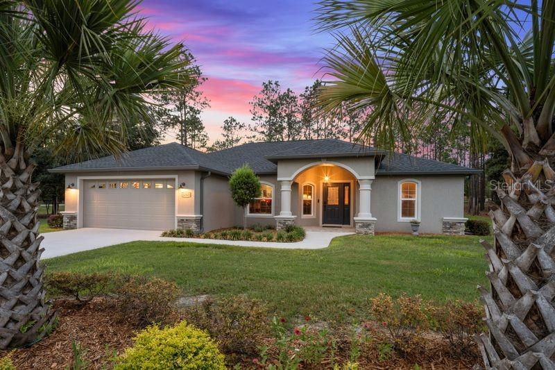 Impeccably maintained 2024 Community Builders Inc. saltwater pool home situated on 2.18 fully fenced acres on a desirable corner lot. This energy-efficient home offers 3 bedrooms, 2 bathrooms, a 2-car garage, and over 2,300 square feet under roof. The open-concept floor plan features luxury vinyl plank flooring, abundant natural light, and a beautifully designed kitchen with quartz countertops, soft-close cabinetry, dovetail drawers, stainless steel appliances, a large center island, and a convenient pass-through window to the lanai. The spacious primary suite includes tray ceilings and a spa-inspired bathroom with dual vanities, soft-close cabinetry, and a floor-to-ceiling tiled walk-in shower. Step outside to your private backyard retreat featuring a screened and heated saltwater pool with waterfall, covered lanai, and professionally landscaped grounds complete with irrigation. Conveniently located just 15 minutes from Dunnellon, Rainbow River, shopping, dining, and medical facilities, and only 20 minutes from Ocala and the World Equestrian Center. Enjoy the benefits of a nearly new home without the wait to build.