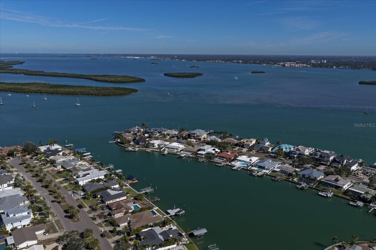 Set within the coveted Island Estates community, this waterfront residence presents an exceptional opportunity to reimagine coastal living in one of the area’s most sought-after enclaves. Offering a generously proportioned and well-designed floor plan, the home provides an impressive sense of space and flow—an ideal foundation for thoughtful updates and customization. A sweeping circular drive and stately double front doors create a grand first impression, opening to an interior where expansive water views immediately command attention. The main living areas are thoughtfully oriented to capture stunning, wide-ranging water vistas, filling the formal living and dining rooms with natural light and creating a seamless connection to the waterfront setting. The centrally located kitchen anchors the home and offers outstanding potential to be transformed into a true gathering space while remaining connected to the surrounding living areas. The primary suite is conveniently located downstairs, providing a private retreat with a walk-in closet and a spacious ensuite bath. Upstairs, three generously sized bedrooms offer flexibility for family, guests, or home office needs. Outdoors, relax poolside, enjoy a refreshing swim after a day on the water, or take advantage of easy access to the Intracoastal and the Gulf beyond. All of this is set within Island Estates, known for its distinctive waterfront lifestyle, boating culture, and proximity to beaches, dining, and shopping.