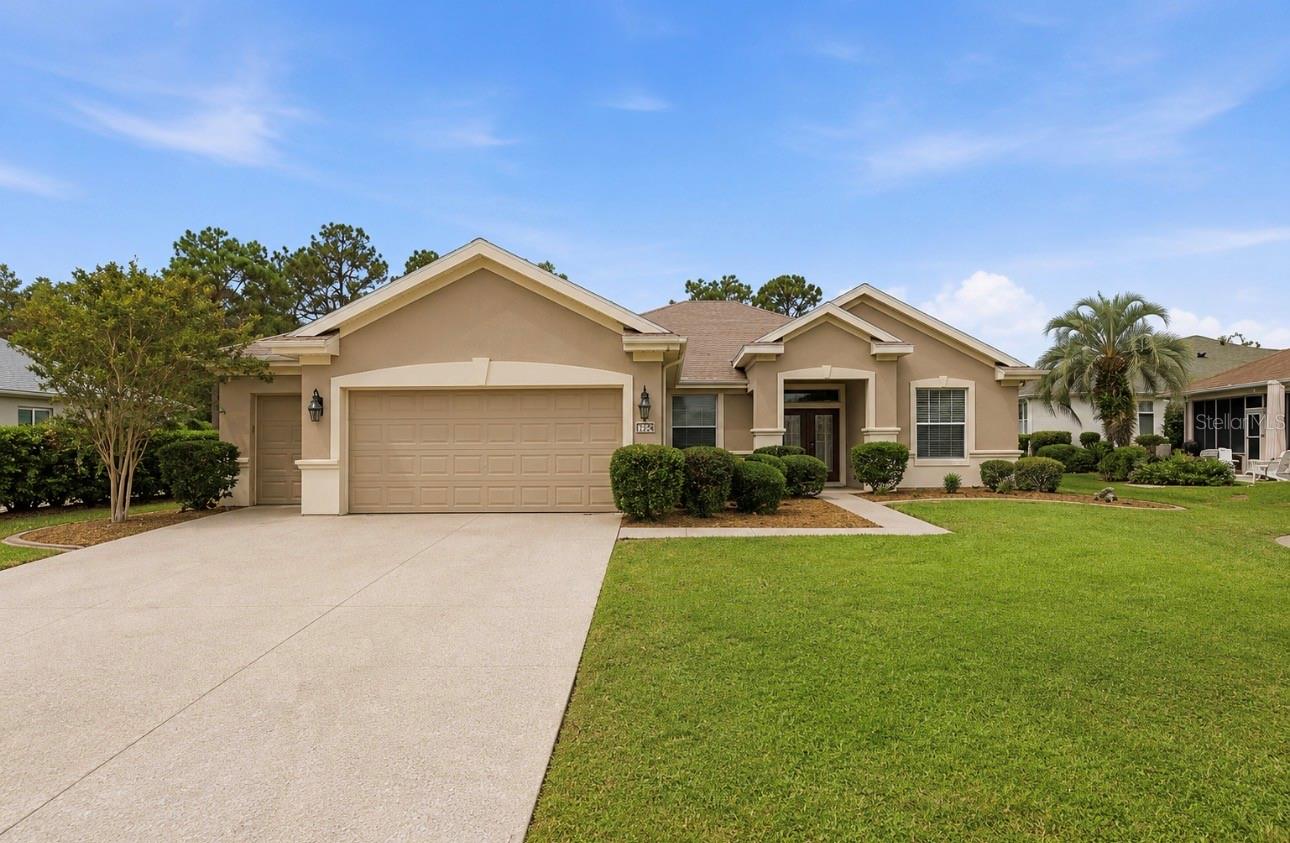 One or more photo(s) has been virtually staged. Stunning Expanded Hanover Floor Plan | 3 Bedrooms + Bonus Room | Golf Course Frontage. Enjoy resort-style living in this beautifully maintained three-bedroom, two-bath expanded Hanover model with a bonus/family room, perfectly positioned on the Memorial Golf Course within Del Webb Spruce Creek Golf & Country Club, one of Central Florida’s premier 55+ gated communities. Built in 2004 and thoughtfully updated, this home offers exceptional curb appeal with a designer-painted driveway and walkway, decorative concrete curbing, and impressive double leaded-glass entry doors that create a grand first impression. The expanded garage features a dedicated golf cart garage and an additional six feet of depth, providing outstanding storage and workspace. Inside, the open and inviting floor plan showcases hardwood flooring throughout all three bedrooms and the bonus room, with tile flooring throughout the remaining living areas—no carpet anywhere. Neutral paint tones and abundant natural light enhance the home’s warm and welcoming atmosphere. The spacious kitchen is designed for both everyday living and entertaining, featuring rich dark maple cabinetry with pull-out shelving, Carian countertops, additional built-in cabinetry in the breakfast nook, and a seamless flow into the great room and dining spaces. A separate formal dining room provides the perfect setting for family gatherings and holiday celebrations. The bonus/family room addition, completed in 2010, offers flexible space ideal for a media room, hobby area, home office, or additional living space. Retreat to the screened Lanai and enjoy peaceful golf course views overlooking the Memorial Course, providing the perfect backdrop for morning coffee, outdoor dining, or taking in Florida’s beautiful sunsets. Roof 2021, HVAC 2018, whole house water filtration system, and tankless water heater.