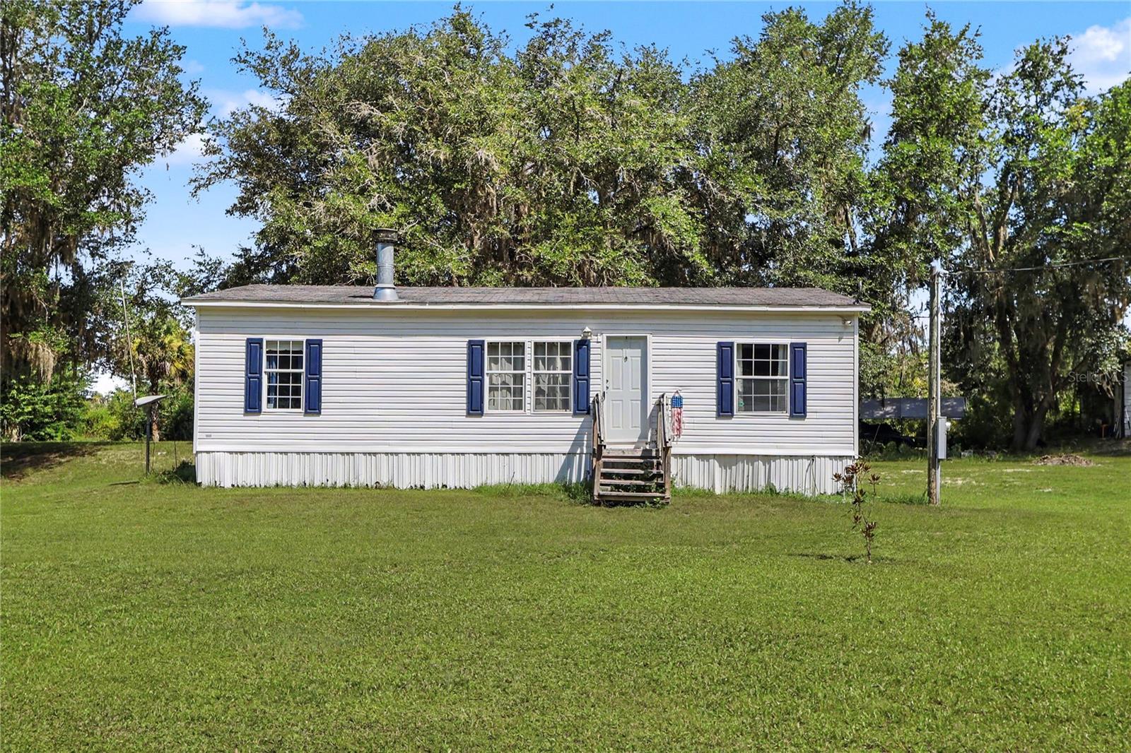 Welcome to your own private slice of country paradise! Nestled on over 4 peaceful acres, this charming 3-bedroom, 2-bath manufactured home offers the perfect blend of comfort, privacy, and functionality. Inside, you'll find a bright, split-bedroom floor plan featuring a cozy wood-burning fireplace, a spacious living area, and an eat-in kitchen designed for everyday living. The primary suite includes a walk-in closet and a private bath, while two additional bedrooms provide space for family, guests, or a home office. Step outside and enjoy the beauty of the surrounding property, complete with mature trees and plenty of room for gardening, recreation, or your favorite outdoor hobbies. A 22' x 31' detached garage/workshop with electricity provides exceptional space for projects, equipment, storage, or a home-based business. Recent improvements, including a newer roof, HVAC system, and water treatment system, add peace of mind. With A-1 agricultural zoning, no HOA, and room to roam, this property offers endless possibilities for those seeking a relaxed country lifestyle.
Conveniently located with easy access to Ocala and Gainesville, you'll enjoy the tranquility of rural living while remaining close to shopping, dining, and everyday conveniences. Whether you're looking for a full-time residence, a weekend retreat, or a property with room to grow, this one is ready to welcome you home.
