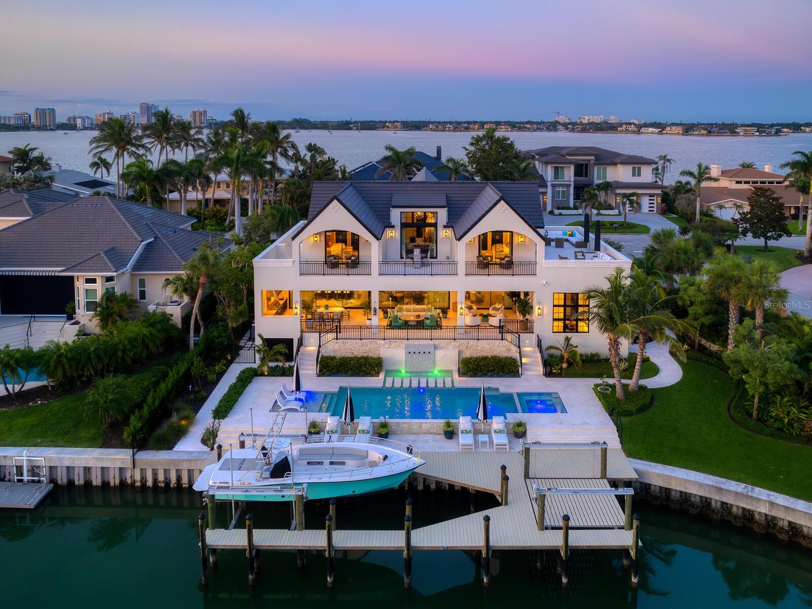 A breathtaking fusion of architectural brilliance and design sophistication, 440 Meadow Lark Drive is arguably the finest residence ever constructed in Sarasota. Envisioned by the masterful minds of architect Clifford Scholz and Voigt Brothers Construction, this custom estate is a testament to elevated living where no detail has been spared. From the moment you approach the bespoke exterior elevations, crafted to distinguish with striking individuality you realize this is not merely a home, but a work of art. Step inside to discover nearly 7,000 square feet of flawlessly curated interiors where each room tells a story.  Italian oak floors, Gucci, Phillip Jeffries, and Holly Hunt wallpapers, and SAWW’s custom cabinetry set the tone for refined elegance. Every room is inspired by the glamor of Kelly Wearstler’s Hollywood Regency style and brought to life by renowned designer Christiana Engert, while the entire home functions as a smart residence, seamlessly blending intuitive technology with timeless luxury. At the heart of the home, the kitchen is both showpiece and workspace, featuring Dolomite marble counters with protective tough-skin, double dishwashers, Wolf, Sub-Zero, and Miele appliances, and a hidden pantry with display cabinetry, wine chiller, and artwork. The adjacent morning room is perfect for casual lounging, complete with custom cabinetry and a discreet TV. The living room exudes warmth with a Nero Marquina marble gas fireplace, generous seating, and captivating water views, while the dining room stuns with a one-piece luxe side table and a dramatic custom chandelier. Entertain effortlessly in the media room with surround sound, three TVs, and a custom bar.  An adjacent butler’s pantry includes an additional refrigerator, washer/dryer, dishwasher, and concealed storage.  The 1400+ bottle wine cellar is a masterpiece unto itself.  With custom artistic designs, backlit lighting, and a commercial capacity cooling system, the one-of-a-kind space is perfect for the most discerning collector.  The primary suite is a sanctuary of indulgence with hand-painted wallpaper, sweeping waterway views, and his-and-her closets with exquisite built-ins, chandelier, a marble island, and boutique-style jewelry displays. The spa bathroom features gold-leaf inspired tile, dual vanities, and indoor and outdoor showers. Ascend the single-piece staircase to the upper level, where guest suites are equally impressive with vaulted ceilings, en-suite baths, and private access to the second-floor entertainment terrace. A loft with clerestory windows, serving bar, and hidden storage provides flexibility as a guest lounge, office, or retreat. A separate-access guest suite doubles as an office or bonus room, with its own bath and dramatic architectural lines. Outdoors, resort-level amenities await. The lanai offers seamless indoor-outdoor flow through oversized sliders, a full outdoor kitchen, fireplace, and multiple seating areas beneath tongue-and-groove ceilings. Limestone pavers surround a saltwater pool and spa designed for comfort and elegance, while a 20,000 lb boat lift and 7,000 lb deck lift for kayaks or paddleboards make this an ideal waterfront escape. Stunning privacy landscaping by Michael A. Gilkey ensures serenity across the grounds. With concrete walls on both levels, an 8-inch concrete slab second floor, full-house generator, whole-house water softener, and natural gas, this estate combines enduring structure with breathtaking beauty.