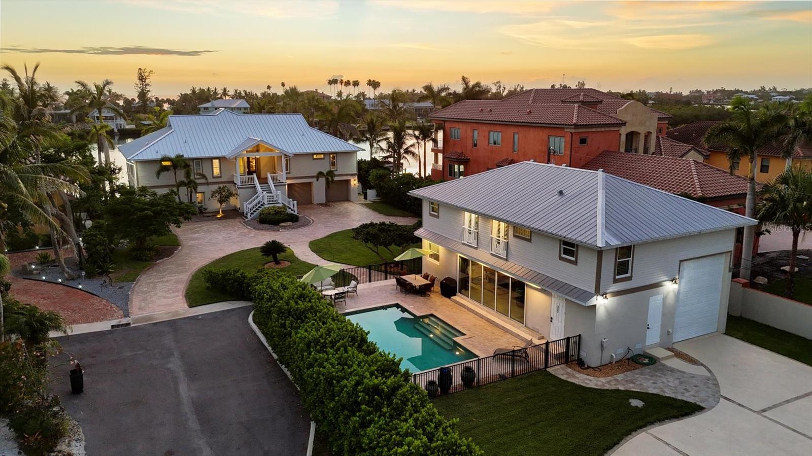 Under contract-accepting backup offers. Set along the coveted waterfront of Blackburn Bay, this rare Nokomis estate embodies the very best of refined coastal living with multi-residence flexibility. The .68-acre property spans 100 waterfront feet and offers a stunning main residence and a fully appointed guest house with unique and flexible garage space. Crafted for effortless entertaining, year-round comfort, and Gulf Coast adventure, it encompasses 4,537 square feet of living space, four bedrooms, four-and-a-half baths, an attached garage, and dedicated boat, RV or hobby storage, ideally pairing casual luxury with a practical lifestyle. A welcoming approach leads to Trex steps, and a front porch framed by glass-pane French doors, opening to expansive living spaces. The great room’s illuminated tray ceiling, large windows, and engineered hardwood floors set the tone for airy sophistication. The dining area, open to the kitchen and living area, features sliders to the deck, designer lighting and a decorative high ceiling. The chef’s kitchen offers an oversized central island with seating, quartz countertops, a premier stainless-steel appliance package with a cabinet-faced Sub-Zero refrigerator, stone backsplash, and ceiling-height cabinetry with decorative glass accents. A custom bar and lounge, with prep sink, wine cooler, dual Sub-Zero beverage refrigerators, glass-faced cabinetry and a hidden door to the primary suite, adds a touch of intrigue. The primary bedroom includes a sitting area, dual walk-in closets, and plantation-shuttered windows, while its spa-inspired bath features a soaking tub, glass-block walk-in shower, dual vanities, water closet, chandelier-lit tray ceiling and transom windows. Two guest bedrooms share a full bath, and a half bath completes the main floor. The ground level, finished with wood-look tile, offers water views and flexible spaces that open to the outdoor amenities, abundant storage and a two-stop elevator. Outdoor living is elevated with a spacious terrace featuring retractable awning and hurricane screens, a shaded lower patio with freshly sealed stone columns and mature landscaping. The dock includes two lifts, plus water, electric and lighting for seamless boating with quick access to the Gulf. The guest house is equally well-appointed, with a travertine-floored great room, kitchenette with stainless steel Frigidaire appliances, upstairs family room and bedroom, two full baths, Bosch laundry, and a garage designed for boat, RV or hobby storage. Multiple French doors and sliders connect the space to an amazing paver pool area strategically between the two homes. With its blend of refined interiors, generous indoor-outdoor spaces and direct waterfront access, 559 Bob Hope Drive is more than a home, it’s a statement of coastal living.
