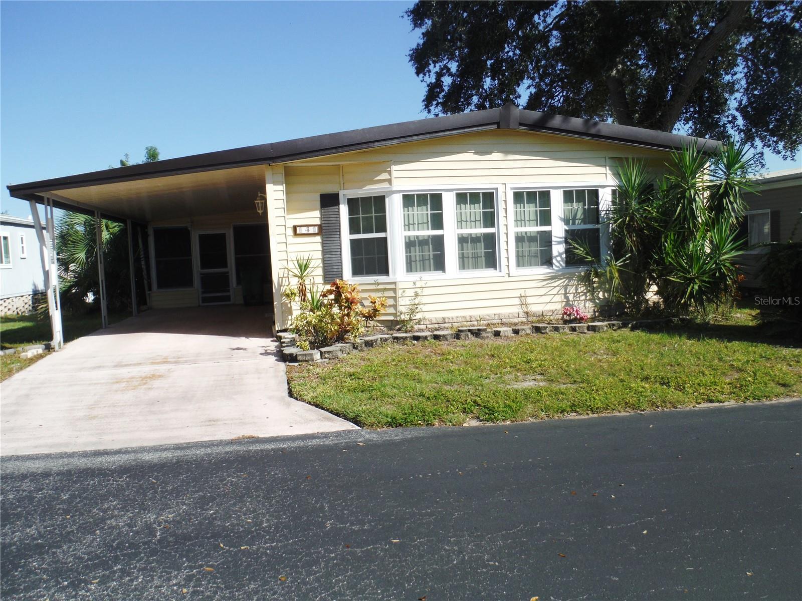 This 2 bedroom 2 bath with an office allows a cat or a dog up to 25 pounds. The large open Living and dining rooms have laminate floors.  Everything is very open with an island kitchen and family room with a skylight. There are 2 pantries and a storage closet in the kitchen.  This home is 1354 square feet.  There is also a side porch with windows & a storage shed with washer & dryer. You own the 52X75 lot included in the price.  All you pay is $250 per month for maintenance fee which includes water, sewer, trash, lawn, private roads, clubhouse, heated pool & spa, gym, pickleball, and a lot where you can park your RV or your boat.  This is a very friendly 55+ community with winding roads, little hills, lakes, and backs up to the bay.  Room measurements approximate.