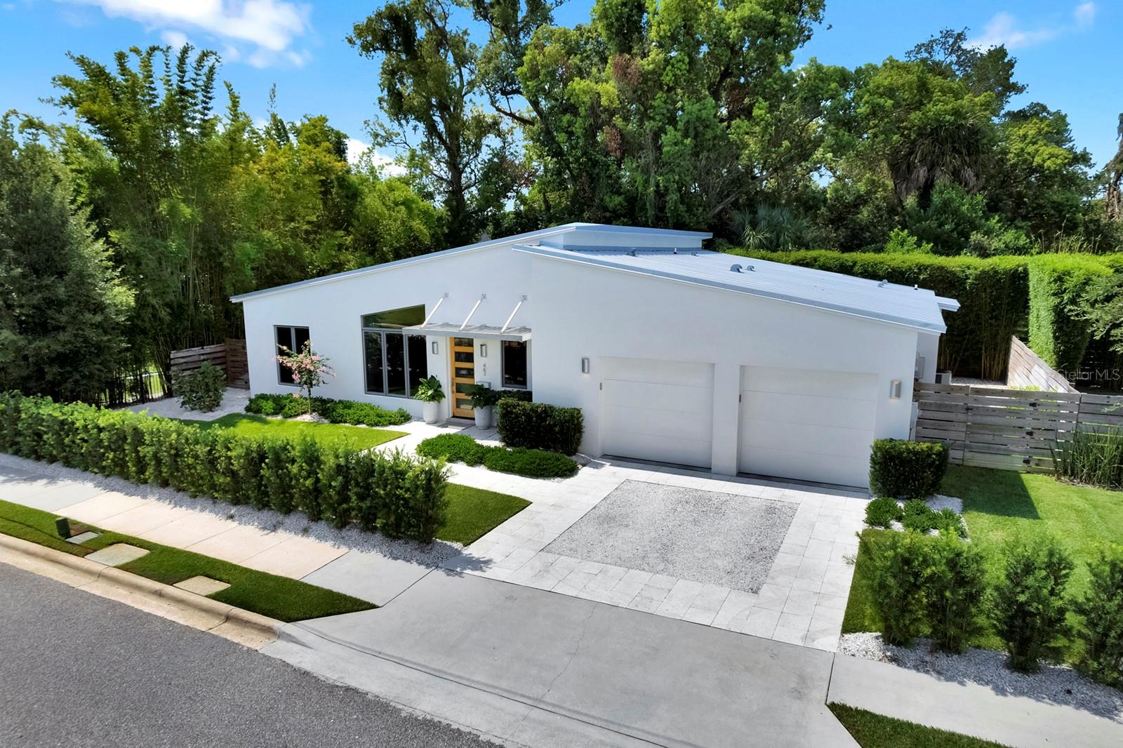 In the heart of Winter Park's vibrant Hannibal Square, this exceptional one-story residence, completed in 2022, offers the ideal blend of contemporary design, refined finishes and an unbeatable accessible lifestyle. Thoughtfully designed with three bedrooms, two and one-half baths, and an open-concept floor plan, the home showcases clean architectural lines, soaring ceilings and walls of glass that fill the interior with natural light while framing views of the beautifully landscaped grounds. The chef's kitchen serves as the centerpiece of the home, featuring premium Wolf and Sub-Zero appliances, custom cabinetry, a center island with seating, and workspace for everyday living and entertaining. The adjoining dining area flows seamlessly into the spacious great room, where custom-built library shelving creates a striking focal point and adds warmth and character to the modern design. Beautiful polished concrete floors extend throughout the residence, providing a cohesive and sophisticated aesthetic. Designed with privacy in mind, the split-bedroom floor plan places the primary suite in its own secluded wing. This spacious retreat offers direct access to the covered rear patio and features a beautiful bath with dual vanities, an oversized walk-in shower, private water closet, and an impressive custom walk-in closet measuring approximately 11 by 9 feet. Conveniently accessible from the primary bath and laundry room, the thoughtfully designed closet enhances everyday functionality. On opposite side of the home, two additional guest bedrooms are connected by a well-appointed Jack-and-Jill bath, while a stylish powder bath is ideally located for visitors. Outdoor living is equally inviting with a covered patio with a privacy bamboo hedge that creates a peaceful backdrop for relaxing or entertaining. An attached two-car garage completes this beautifully appointed residence. Ideally near the acclaimed restaurants, wine bars, coffee shops, and boutiques of Hannibal Square, this home offers one of Winter Park's desirable lifestyles. Visit the renowned shopping, dining, galleries and sidewalk cafés of Park Avenue, enjoy nearby Central Park and community events, or take advantage of the proximity to Rollins College, the Winter Park Farmers' Market and major roadways providing convenient access throughout Central Florida. This is a rare opportunity to enjoy nearly new construction in one of Winter Park's sought-after neighborhoods, where modern luxury and exceptional accessibility come together.