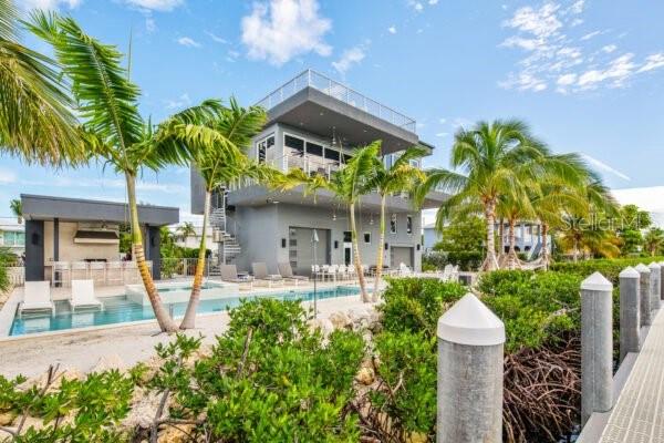 Stunning Furnished Coastal Modern 3-bedroom, 3-bath modern waterfront estate built by the Florida Keys' premier builder, D'Asign Source. This three-story solid concrete home offers exceptional design, craftsmanship, and strength, perfectly positioned on over a quarter acre with 110 feet of deep-water frontage along a 300-foot-wide canal. Boaters will love the 10,000 lb boat lift, 85 feet of dockage, and direct deep-water access to the Gulf and Atlantic. A fish cleaning station with water, bait freezer, and commercial ice machine make this property a dream for anglers and water enthusiasts. Inside, expansive glass doors and windows flood the living space with natural light and showcase panoramic canal views. The chef's kitchen features Viking appliances, quartz countertops, wine cooler, and premium finishes, while the open-concept design connects seamlessly to multiple balconies and outdoor living areas. The master suite includes an oversized rainfall shower and a private balcony overlooking the water, while two guest bedrooms provide bright, inviting retreats. Outdoor living is the heart of this home, featuring a custom 440 sq. ft. pool with hot tub and sunshelf, surrounded by soft sand, hammocks, and lush tropical landscaping. Entertain in style at the covered outdoor bar and grilling area, or unwind with sunsets from the private rooftop lounge overlooking the Gulf of Mexico. Additional features include four+ parking spaces, trailer parking, high-speed WiFi, multiple smart TVs, and a fully fenced yard that's pet-friendly. Tis property combines luxury, durability, and a true Keys lifestyle — offering modern design, deep-water access, and spectacular views in one of Marathon's most sought-after waterfront neighborhoods.