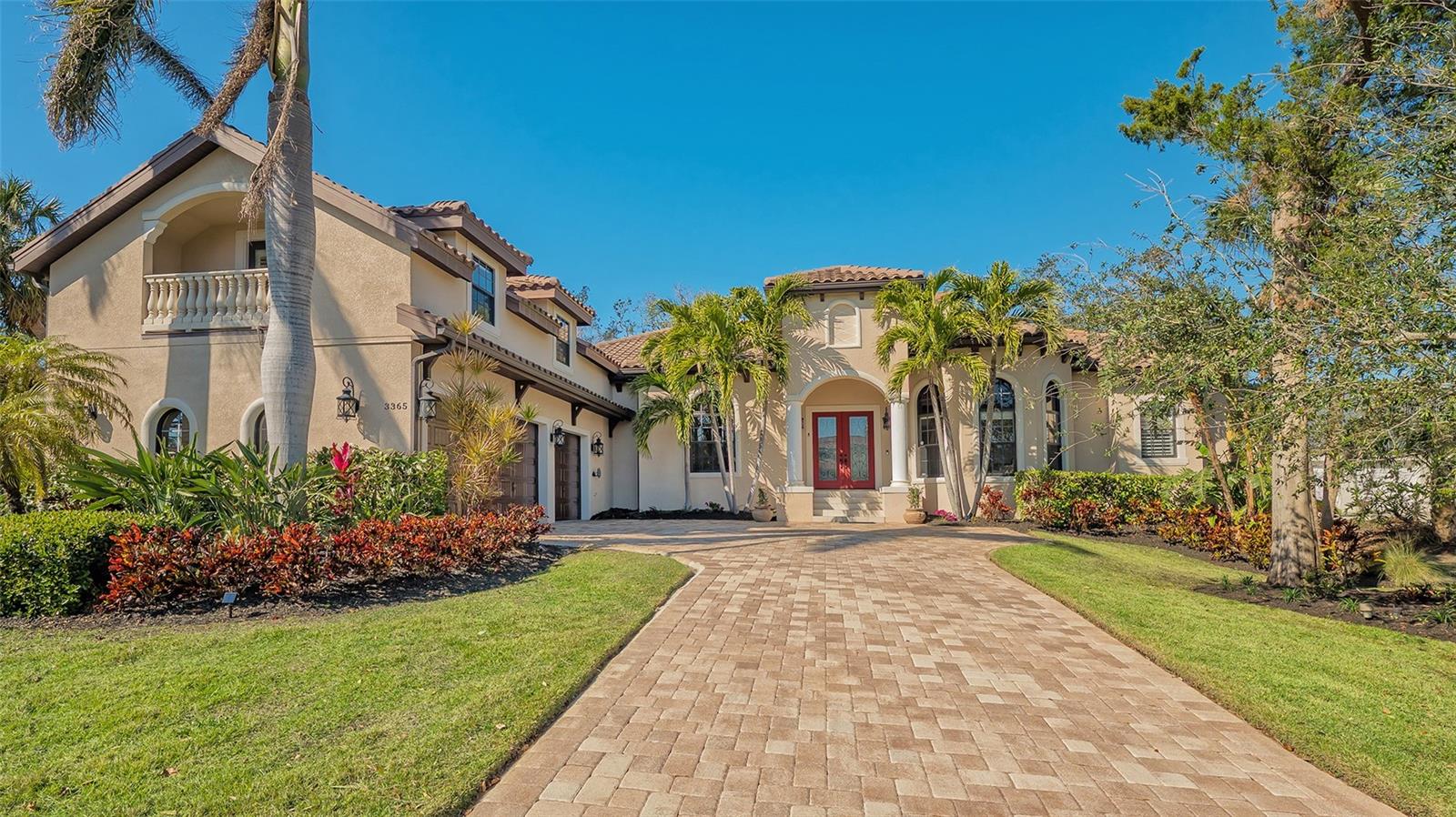 Discover coastal luxury in the prestigious, 24-hour guard-gated Bay Isles Bayou community on Longboat Key. Tucked away on a quiet cul-de-sac, this executive-style home sits on nearly a third of an acre, surrounded by lush tropical landscaping and mature oaks. Boasting over 3,500 square feet of refined living space, this 4-bedroom, 4.5-bathroom residence offers an inviting blend of elegance and comfort. A pavered driveway leads to a spacious three-car garage, with a private carriage house suite above—ideal for guests or extended stays. Inside, crown molding and tray ceilings enhance the expansive living room, where a designer fireplace and feature wall create a striking focal point. Warm hickory hardwood floors span the main level, with oversized Carrera tile adding a sleek touch to the kitchen. The open-concept kitchen is a chef’s dream, featuring a large island, breakfast bar seating, custom cabinetry, modern granite countertops, a glass tile backsplash, and top-of-the-line stainless steel appliances, including a Wolf range. A built-in wet bar with ample storage and dual beverage coolers enhances the space, perfect for entertaining. The primary suite, located on the first floor, is a serene retreat with a tray ceiling, private lanai access, a generous walk-in closet, and a luxurious ensuite with dual vanities, a walk-in shower, and a soaking tub. Two oversized guest suites, each with beautifully designed bathrooms, and a versatile den complete the main level. A well-appointed indoor laundry room offers ample storage and counter space. Designed for seamless indoor-outdoor living, a wall of sliding glass doors opens to the screened lanai, where a resort-style pool and spa set the stage for relaxation. The outdoor kitchen, equipped with granite countertops, a farm sink, a premium gas grill, and a mounted flat-screen TV, makes entertaining effortless. A convenient pool bathroom adds to the thoughtful layout. As a resident of Bay Isles, enjoy exclusive access to the Bay Isles Beach Club, a private, residents-only retreat with pristine sandy shores, a picnic area, restrooms, and dedicated parking. Situated near the Publix shopping plaza and just moments from the world-class dining and boutiques of St. Armands Circle, this exceptional home also offers easy access to Sarasota’s vibrant cultural attractions. Whether you're looking for a private coastal sanctuary or an entertainer’s dream home, this Longboat Key masterpiece delivers the best of Florida living.