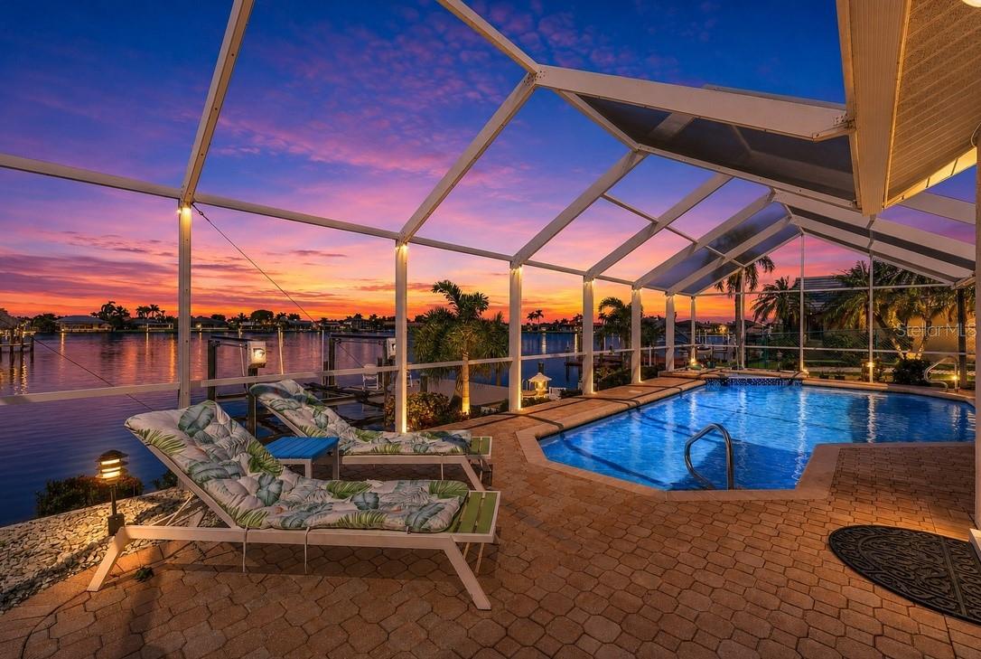 Discover Your Gulf Access Dream Home on Lake Britannia of the Desirable 8 Lakes Neighborhood. Have you been looking for and updated pool home that combines BIG water views and quick boating access? Look no further as this stunning 3-bedroom home offers the perfect blend of style, comfort, and convenience. With gulf access and a new shingle roof (2022), this property features a 2-car garage, circular driveway, and fresh, tropical landscaping accented by gravel transitions. Enjoy year-round outdoor living with a solar and electric heated pool, complete with a relaxing water feature and a spacious pavered pool deck. The large screened-in lanai provides plenty of room to lounge, dine, and BBQ. For boating enthusiasts, the oversized composite dock features captain's walk and boat lift operated by a wireless remote, ready for all your water adventures. Bridge height is 8.75 feet at high tide and it take approximately 15 minutes to reach open water at idle speed through the picturesque Rose Garden. Best of all, flood insurance is not required thanks to the property’s recent LOMA (Letter of Map Amendment) status. Inside, you’ll be greeted by vaulted ceilings and breathtaking views of the pool and water beyond. The home offers two living areas, one of which features a cozy stacked stone fireplace and wood beam ceiling. An additional flex space can serve as a game room, office, den, or kids' playroom. The kitchen is a chef's delight with granite countertops, soft-close cabinets, and stainless steel appliances. The kitchen island is perfect for casual meals, while the pass-through window makes it easy to serve guests on the lanai. The primary bedroom offers a large walk-in closet with a built-in closet system and a spacious en-suite bathroom featuring wood-toned cabinets, granite countertops, dual sinks, and an expansive walk-in shower filled with natural light. New additions include a brand new pool pump (April 2025) and pool cage screws. Additional highlights include a pool bathroom with dual sinks and walk-in shower, a fenced dog run, and a laundry room with extra storage and a laundry sink. Whether you’re enjoying breakfast from the kitchen table or relaxing on the lanai, you'll often spot manatees, dolphins, and fish right outside. Every day brings new surprises depending on the season and time of day. On perfect weather days, you can open the sliders to seamlessly blend indoor and outdoor living. This is waterfront living at its finest—schedule your showing today!