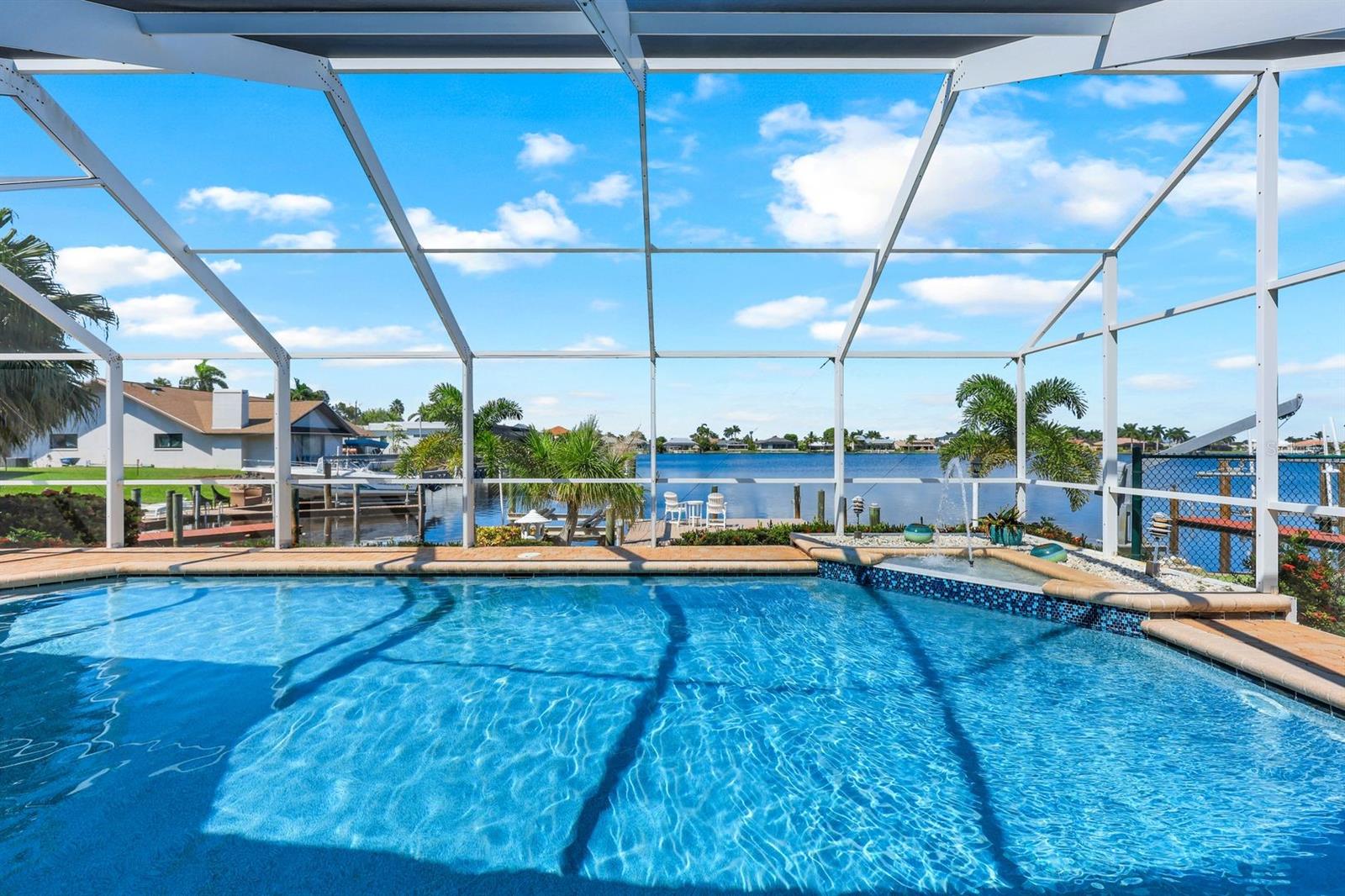 Discover Your Gulf Access Dream Home on Lake Britannia of the Desirable 8 Lakes Neighborhood. Have you been looking for and updated pool home that combines BIG water views and quick boating access? Look no further as this stunning 3-bedroom home offers the perfect blend of style, comfort, and convenience. With gulf access and a new shingle roof (2022), this property features a 2-car garage, circular driveway, and fresh, tropical landscaping accented by gravel transitions. Enjoy year-round outdoor living with a solar and electric heated pool, complete with a relaxing water feature and a spacious pavered pool deck. The large screened-in lanai provides plenty of room to lounge, dine, and BBQ. For boating enthusiasts, the oversized composite dock features captain's walk and boat lift operated by a wireless remote, ready for all your water adventures. Bridge height is 8.75 feet at high tide and it take approximately 15 minutes to reach open water at idle speed through the picturesque Rose Garden. Best of all, flood insurance is not required thanks to the property’s recent LOMA (Letter of Map Amendment) status. Inside, you’ll be greeted by vaulted ceilings and breathtaking views of the pool and water beyond. The home offers two living areas, one of which features a cozy stacked stone fireplace and wood beam ceiling. An additional flex space can serve as a game room, office, den, or kids' playroom. The kitchen is a chef's delight with granite countertops, soft-close cabinets, and stainless steel appliances. The kitchen island is perfect for casual meals, while the pass-through window makes it easy to serve guests on the lanai. The primary bedroom offers a large walk-in closet with a built-in closet system and a spacious en-suite bathroom featuring wood-toned cabinets, granite countertops, dual sinks, and an expansive walk-in shower filled with natural light. New additions include a brand new pool pump (April 2025) and pool cage screws. Additional highlights include a pool bathroom with dual sinks and walk-in shower, a fenced dog run, and a laundry room with extra storage and a laundry sink. Whether you’re enjoying breakfast from the kitchen table or relaxing on the lanai, you'll often spot manatees, dolphins, and fish right outside. Every day brings new surprises depending on the season and time of day. On perfect weather days, you can open the sliders to seamlessly blend indoor and outdoor living. This is waterfront living at its finest—schedule your showing today!