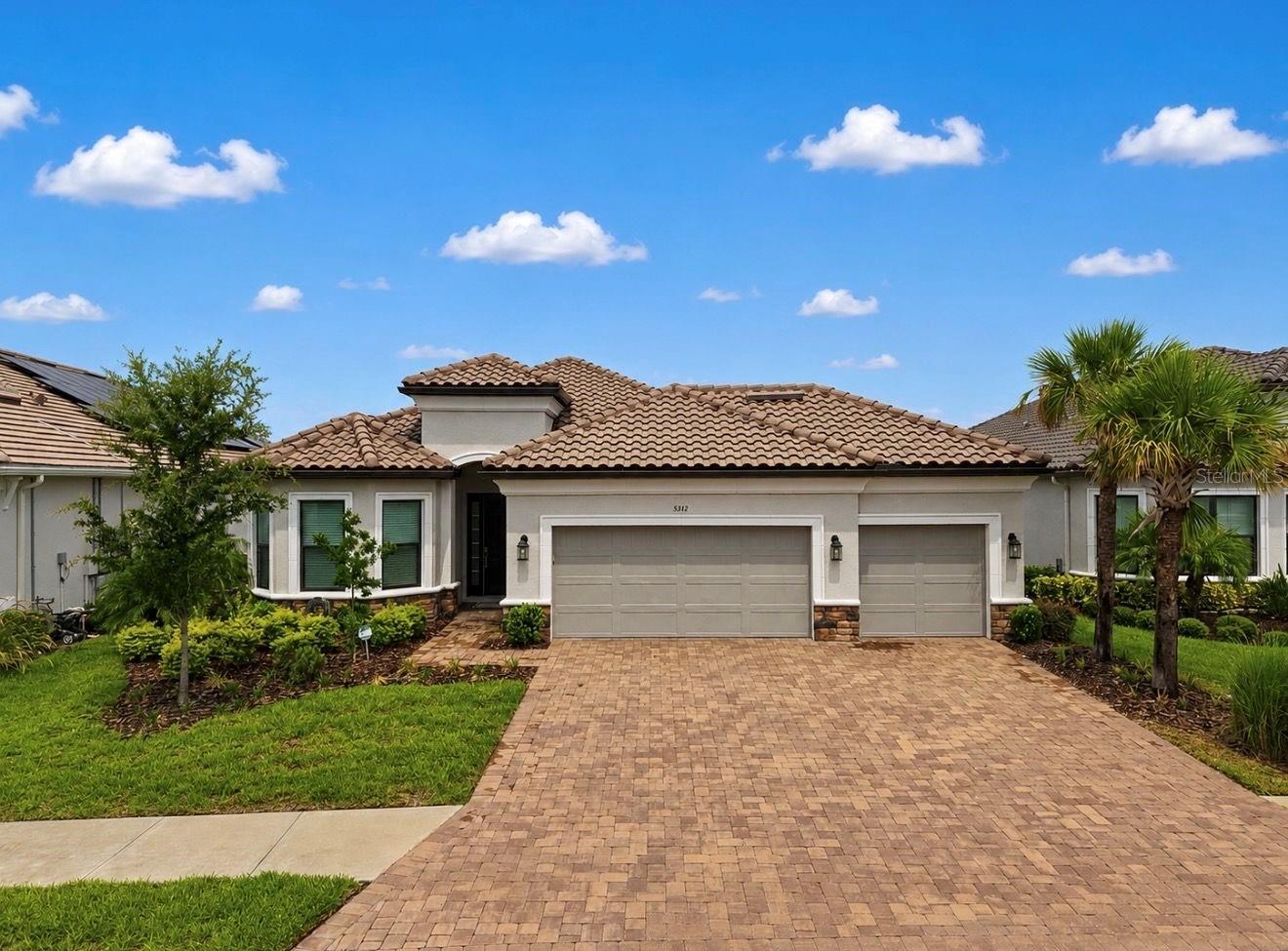 Perfectly positioned on one of Esplanade at Artisan Lakes' premier WATER VIEW homesites, this beautifully upgraded Taylor Morrison Lazio model, built in 2024, offers an exceptional combination of quality craftsmanship, designer finishes, and resort style outdoor living. Featuring approximately 2,332 square feet, this move in ready residence includes 3 bedrooms, a private den, 3 full bathrooms, and an oversized 3 CAR GARAGE. Located OUTSIDE THE FLOOD ZONE with NO FLOOD INSURANCE REQUIRED, the home is ideally situated with convenient access to I-75 and I-275, placing Tampa, St. Petersburg, Sarasota, premier shopping, dining, airports, and the Gulf Coast's award-winning beaches within easy reach.
Designed for comfortable everyday living and effortless entertaining, the open-concept floor plan is filled with natural light and showcases soaring ceilings, designer wall treatments, and seamless indoor and outdoor living. The gourmet kitchen serves as the heart of the home, featuring quartz countertops, timeless cabinetry, premium stainless-steel appliances, abundant storage, and an oversized center island overlooking the spacious great room and dining area.
The private primary suite is a peaceful retreat highlighted by a charming bay window framing tranquil pond and pool views. The spa inspired ensuite features dual vanities, an oversized walk-in shower, and a custom designed walk-in closet offering exceptional organization and storage. Two generously sized guest bedrooms and two additional full bathrooms provide comfort and privacy for family and visitors, while the private den behind French doors offers the flexibility of a home office, library, media room, or guest space.
Designed to embrace Florida's year-round lifestyle, the expansive screened lanai is the home's signature gathering space. Enjoy a HEATED SALTWATER POOL, HEATED SPA, FULLY EQUIPPED OUTDOOR KITCHEN, motorized lanai screens, ceiling fans, built in entertainment speakers, and tranquil waterfront views that create an exceptional outdoor living experience.
Residents of Esplanade at Artisan Lakes enjoy a nearly 7,000 square foot clubhouse, resort style pool, resistance pool, spa, fitness center, movement studio, tennis, pickleball, billiards, dog park, fire pit, scenic walking trails, and a full time Lifestyle Director who coordinates an active calendar of clubs, fitness classes, and social events.
Beautifully maintained, thoughtfully upgraded, and ideally situated on one of the community's most desirable waterfront homesites, this exceptional residence presents a rare opportunity to enjoy refined Florida living in one of Palmetto's premier gated communities.
