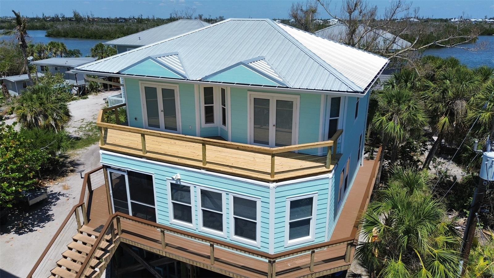 This beautiful 3 bedroom, 3 bath home is located on Little Gasparilla Island, a bridgeless barrier island off the Cape Haze Peninsula, accessible by private boat or water taxi only. The island is just a short 10-minute ride across the bay, offering a tranquil escape from the hustle and bustle of the mainland. Here, you can truly unwind and let your stress melt away. This home is located in Banyan Bayou, a land condominium community, where you have a 1/7 undivided interest in this gulf to bay property, a community deep water dock, and deeded beach access. The HOA fee is on an as needed basis. The home was built in 2007 and was renovated after hurricane Ian in 2022 to include a new metal roof, hardy board siding, new luxury vinyl floors throughout the home, fully renovated kitchen with cabinetry, stainless-steel appliances; stove, microwave, dishwasher, French door refrigerator, wine cooler, ceiling fans in all rooms, and the wrap around deck and upper balcony had the decking and railings with stainless steel wire replaced. In 2024 the home was beautifully furnished. On the first floor, a kitchen that would make any chef happy has beautiful granite counter tops and a large island with dining area and closet pantry, a full bath with beautiful shower tile, travertine floors and granite countertop, large laundry room with travertine floors and shelving for storage, den/3rd bedroom with pocket doors, large living room, and screened in porch. On the second floor, are two primary suites with French doors leading out to the open balcony, facing west, with partial views of the gulf. Both ensuite bathrooms have beautiful wall tile, granite countertops and travertine floors. Downstairs, under the house is a large porch, dining area, a fire pit area, storage shed large enough to hold all your fishing tackle, beach toys and golf cart, and an outdoor shower. Little Gasparilla Island does not have grocery stores, restaurants, or shops, but it does offer 3 ½ miles of pristine, uncrowded beaches, ideal for collecting seashells and shark’s teeth, swimming, or simply relaxing in the sun with a good book. The surrounding waters provide excellent fishing opportunities for redfish, snook, snapper, trout, and more. By water, you can easily reach a variety of delightful dock-side restaurants. As the day ends, neighbors often gather by the water’s edge to watch the sunset, concluding another blissful day in this island paradise. Come and discover this lovely home, embrace the unique lifestyle it offers, and experience what it truly means to live on island time.