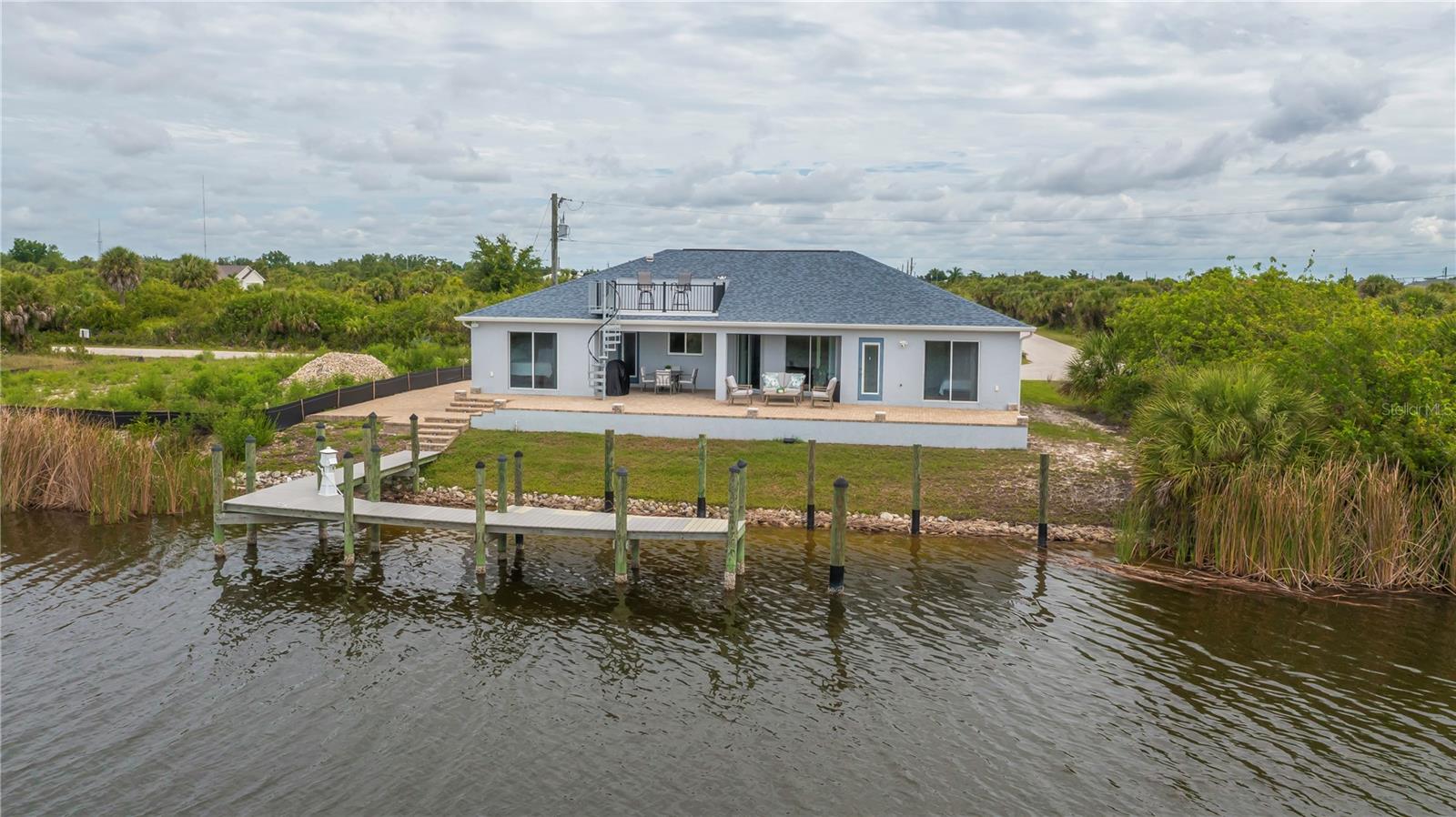 PREPARE TO BE WOWED by this unbelievably stunning, custom crafted 2020 newly built MASTERPIECE in the highly sought after South Gulf Cove boating community! This exquisite 3 bedroom, 3 bathroom, 3 CAR GARAGE home offers PREMIUM SAILBOAT GULF ACCESS and an array of luxurious extras that set it apart from the rest. From the moment you arrive, the impressive curb appeal captivates with a paver lined CIRCULAR DRIVEWAY, tropical palm trees and grand columns framing the soaring covered entryway. Step inside to a light filled foyer featuring elegant tray ceilings, European inspired details, and spectacular plank style tile flooring throughout. Gorgeous WIDE WATER VIEWS greet you from nearly every room, creating an atmosphere of tranquility and grace. At the heart of the home, the chef worthy kitchen shines with fine imported cabinetry, designer hardware, and a convenient pass through to the patio. The breakfast bar dazzles with glass accents and a unique chartreuse service style lazy susan, perfectly complemented by top of the line stainless steel appliances and luxurious stone countertops ideal for all your entertaining desires. The spacious living and dining area flow seamlessly in an open concept split floor plan, sliding effortlessly outdoors to your private waterfront oasis. The primary bedroom is a zen retreat with private patio access, long canal views, dual closets, privacy transit window for star gazing views, tray ceiling and a spa inspired ensuite bathroom featuring superior finishes, breathtaking vanity and a Roman style multi setting shower that spells pure indulgence. Guest bedrooms offer generous space, soaring ceilings, and large closets, sharing a stunning middle bath.The back bedroom doubles as a second master with private patio access, unique wet style pool bath, and a custom pass through towel closet that is perfect for guests or family. Outdoor living is unparalleled with a covered paver patio and a spiral staircase leading to a romantic ROOFTOP BALCONY boasting endless water views and serene southern exposure. Whether watching breathtaking sunrises, relaxing in nature’s embrace, or entertaining guests, this space is an idyllic sanctuary. The extended dock accommodates multiple boats and jet skis and offers fishing right from your backyard. Additional perks include a DEDICATE RV PARKING PAD ON SIDE OF HOME, inside laundry, 400-AMP ELECTRICAL SERVICE, TANKLESS hot water heater, ROOM FOR A POOL, generator hookup, and the option to purchase furnishings separately so it can be move in ready. DOUBLE SERVICE DOORS from the 3 car garage allows your mower, golf cart and wide equipment offer effortless entry to and from the side yard. Looking for more space? So many options at an unbeatable price. South Gulf Cove community amenities include a Boat Ramp, nearby marinas, expansive parks, and playgrounds perfect for family fun and outdoor adventures and are OPTIONAL HOA. Enjoy close proximity to fantastic dining, shopping, world class fishing, top golf courses, and so much more. Don’t miss your chance to own this remarkable waterfront jewel where luxury, location, and lifestyle perfectly converge. Don’t Miss out, call TODAY to see this one of a kind SAILBOAT PARADISE FOUND TODAY…YOUR DREAM RESIDENCE AWAITS!