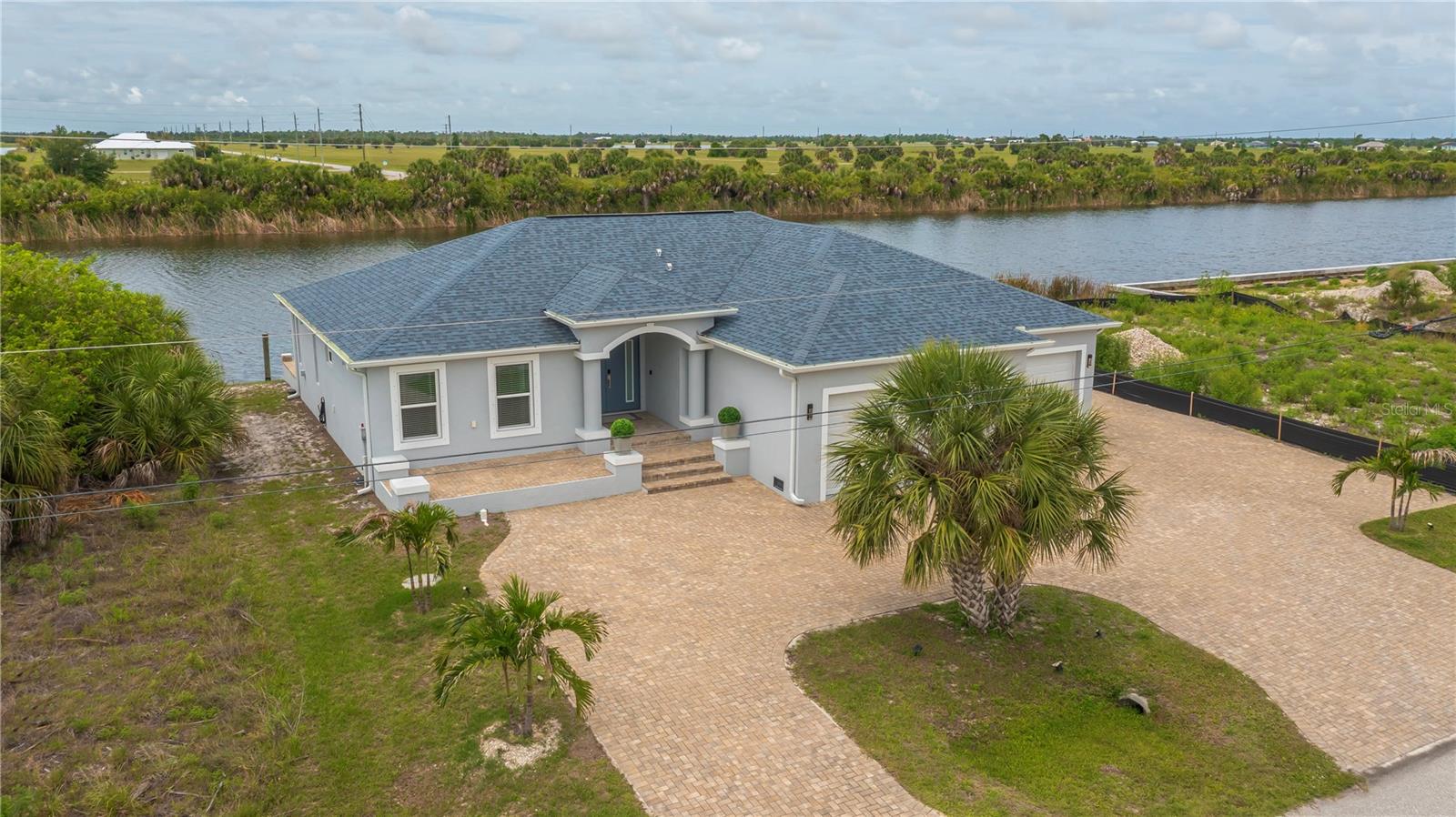PREPARE TO BE WOWED by this unbelievably stunning, custom crafted 2020 newly built MASTERPIECE in the highly sought after South Gulf Cove boating community! This exquisite 3 bedroom, 3 bathroom, 3 car garage home offers PREMIUM SAILBOAT ACCESS and an array of luxurious extras that set it apart from the rest.From the moment you arrive, the impressive curb appeal captivates with a paver lined CIRCULAR DRIVEWAY, tropical palm trees and grand columns framing the soaring covered entryway. Step inside to a light filled foyer featuring elegant tray ceilings, European inspired details, and spectacular plank style tile flooring throughout. Gorgeous WIDE WATER VIEWS greet you from nearly every room, creating an atmosphere of tranquility and grace. At the heart of the home, the chef worthy kitchen shines with fine imported cabinetry, designer hardware, and a convenient pass through to the patio. The breakfast bar dazzles with glass accents and a unique chartreuse service style lazy susan, perfectly complemented by top of the line stainless steel appliances and luxurious stone countertops ideal for all your entertaining desires.The spacious living and dining area flow seamlessly in an open concept split floor plan, sliding effortlessly outdoors to your private waterfront oasis.The primary bedroom is a zen retreat with private patio access, long canal views, dual closets, privacy transit window for star gazing views, tray ceiling and a spa inspired ensuite bathroom featuring superior finishes, breathtaking vanity and a Roman style multi setting shower that spells pure indulgence.Guest bedrooms offer generous space, soaring ceilings, and large closets, sharing a stunning middle bath.The back bedroom doubles as a second master with private patio access, unique wet style pool bath, and a custom pass through towel closet that is perfect for guests or family.Outdoor living is unparalleled with a covered paver patio and a spiral staircase leading to a romantic rooftop balcony boasting endless water views and serene southern exposure. Whether watching breathtaking sunrises, relaxing in nature’s embrace, or entertaining guests, this space is an idyllic sanctuary.The extended dock accommodates multiple boats and jet skis and offers fishing right from your backyard. Additional perks include a dedicated RV/toy parking pad, inside laundry, 400-amp electrical service, instant hot water heater, room for a pool, generator hookup, and the option to purchase furnishings separately so it can be move in ready.Double service doors from the 3 car garage allows your mower, golf cart and wide equipment offer effortless entry from the sideyard. South Gulf Cove community amenities include a Boat Ramp, nearby marinas, expansive parks, and playgrounds perfect for family fun and outdoor adventures and are OPTIONAL HOA.Enjoy close proximity to fantastic dining, shopping, world class fishing, top golf courses, and so much more. Don’t miss your chance to own this remarkable waterfront jewel where luxury, location, and lifestyle perfectly converge. Don’t Miss out, call TODAY to see this one of a kind SAILBOAT PARADISE FOUND TODAY…YOUR DREAM HOME AWAITS!