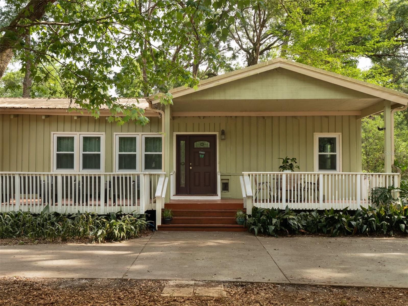 HUGE PRICE REDUCTION…Tucked away on 6.12 beautiful acres, this spacious 4-bedroom, 3-bath home offers the perfect blend of peaceful country living and everyday convenience. Inside, enjoy a newly updated kitchen designed for gathering and entertaining. A durable metal roof adds long-term value and peace of mind. Property features all new windows throughout with lifetime warranty that transfers to the buyer; newly installed leach field; and a water softening system with under sink RO in kitchen installed within the past 2 years.  Relax with morning coffee on the large front porch or unwind in the evenings on the expansive back porch overlooking your private acreage. Plenty of space to bring your animals such as Horses as there are several stalls to board and property is mostly fenced already.  A new metal roof was installed on the garage outbuilding in 2025. Have chickens and other hobbies or simply enjoy the quiet rural lifestyle—all just minutes from Publix and everyday essentials. Best of all, no HOA, giving you the freedom to truly make this property your own. Schedule your showing today.