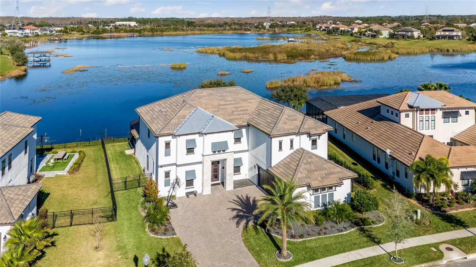 PRICED TO SELL!! 
Step into the lap of luxury with this stunning LAKEFRONT residence in the distinguished Overlook at Hamlin community. This meticulously crafted 5-bedroom, 4.5-bathroom home, spanning over 5,000 sq ft, is a showcase of exceptional upgrades and thoughtful design.

Large wood beams throughout the downstairs create an atmosphere of sophistication. Solid core doors, reinforced walls for television hanging, and built-in internet cable outlets in many rooms underscore the commitment to quality. To add to the ambiance, the primary bedroom and the living room each feature an electric fireplace, adding warmth and elegance to these spaces contributing to the overall luxury of this exceptional residence.

The home features a large rear balcony offering breathtaking views of rocket launches, Disney, and Epcot fireworks. Automatic blinds on all back and side-facing windows and doors, along with black plantation shutters on front-facing windows, provide both convenience and style. Two master suites, one upstairs and one downstairs, offer flexibility and convenience.

The kitchen is a chef's dream with stacker cabinets, a large pantry, high-end MONOGRAM appliances, and a stainless farm sink. Additional touches include a touchless water faucet, filtered water faucet at the sink, and under-cabinet lighting.

The garage is not just a place for cars; it's a well-appointed space with insulated garage doors, a black epoxy floor, and extra shelves and built-ins. A Tesla charger adds to the modern conveniences.

The home boasts a spectacular view of Lake Hancock upon entry, with sliding living room doors leading to a spacious lanai. Enjoy Disney Magic Kingdom fireworks from the backyard, back patio, and upper balcony.

The outdoor oasis features a large pool with a spa and two gas fire bowls. The top-end pool equipment from Pentair ensures a premium experience, and the fully screened enclosure with a high roof line provides an open and expansive feel.

Upstairs, an impressive bar at the entry to the movie (cinema) room is attached to a game area, both connected to an outside balcony. The built-in refrigerator and sink add to the entertainment options.

Bathrooms feature high-end European toilets, and the master bath includes a rain shower head combination. Custom shelving in many closets enhances organization, while the laundry room boasts built-in cabinets and an extra-large upgraded box for media.

This residence is a testament to luxury living, where every detail has been carefully considered to create a home that not only meets but exceeds the highest standards of comfort and elegance.