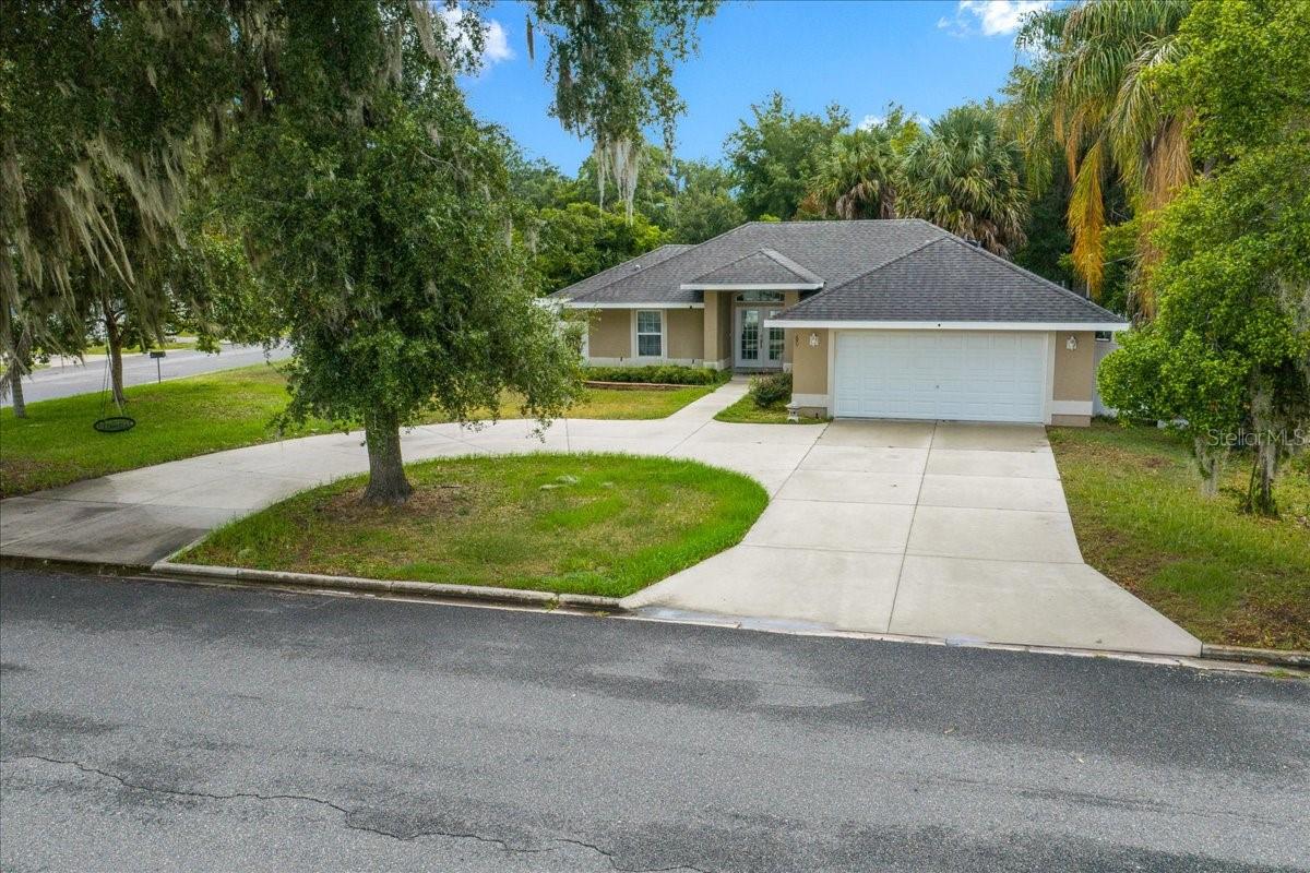 Custom-built in 2018 and offered for the first time, this 3-bedroom, 2-bathroom CBS/stucco residence delivers quality construction, thoughtful design, and exceptional outdoor living on a private, fully fenced third-acre lot in North Umatilla.
Framed by mature oaks and a curved concrete drive, the front of this home makes an immediate impression. A private gated entry leads to the backyard, where a custom timber-frame covered pavilion awaits, featuring recessed lighting, dual ceiling fans, and a floor-to-ceiling stone outdoor fireplace. Purpose-built for entertaining, this outdoor living space is a defining feature rarely found at this price point.
Inside, vaulted ceilings and an open floor plan connect the great room, anchored by a custom built-in fireplace surround, to the dining area and a well-appointed kitchen featuring custom dark wood cabinetry, dramatic granite countertops, a built-in wine rack, walk-in pantry, and stainless-steel appliances. Dishwasher plumbing is already in place behind the cabinetry, should the new owners wish to add one in the future, the infrastructure is there.
The master suite offers a tray ceiling, dual walk-in closets with custom shelving systems, and a spa-inspired en suite bathroom with dual granite vanities, a dedicated vanity station, private water closet, and a floor-to-ceiling tiled walk-in shower with mosaic accent detail.
Additional features include tile flooring throughout, Samsung front-load washer and dryer, 2-car garage, no HOA, and no CDD.
Owner-built. Never previously listed.
